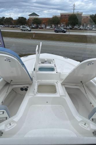 2026 Robalo 246 Cayman boat with open storage compartments, parked near a road.