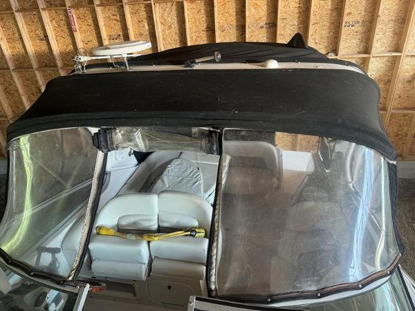 2005 Four Winns 298 Vista boat with black canopy in a garage.