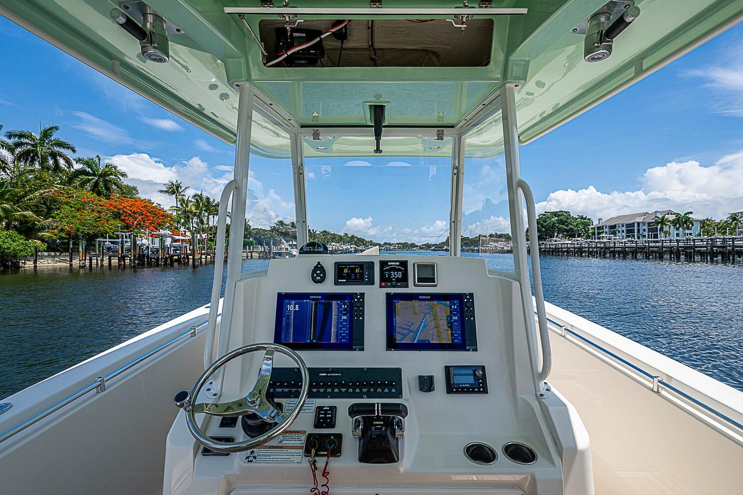 2019 Cobia 320 Center Console boat dashboard with navigation screens, steering wheel, and waterfront view.