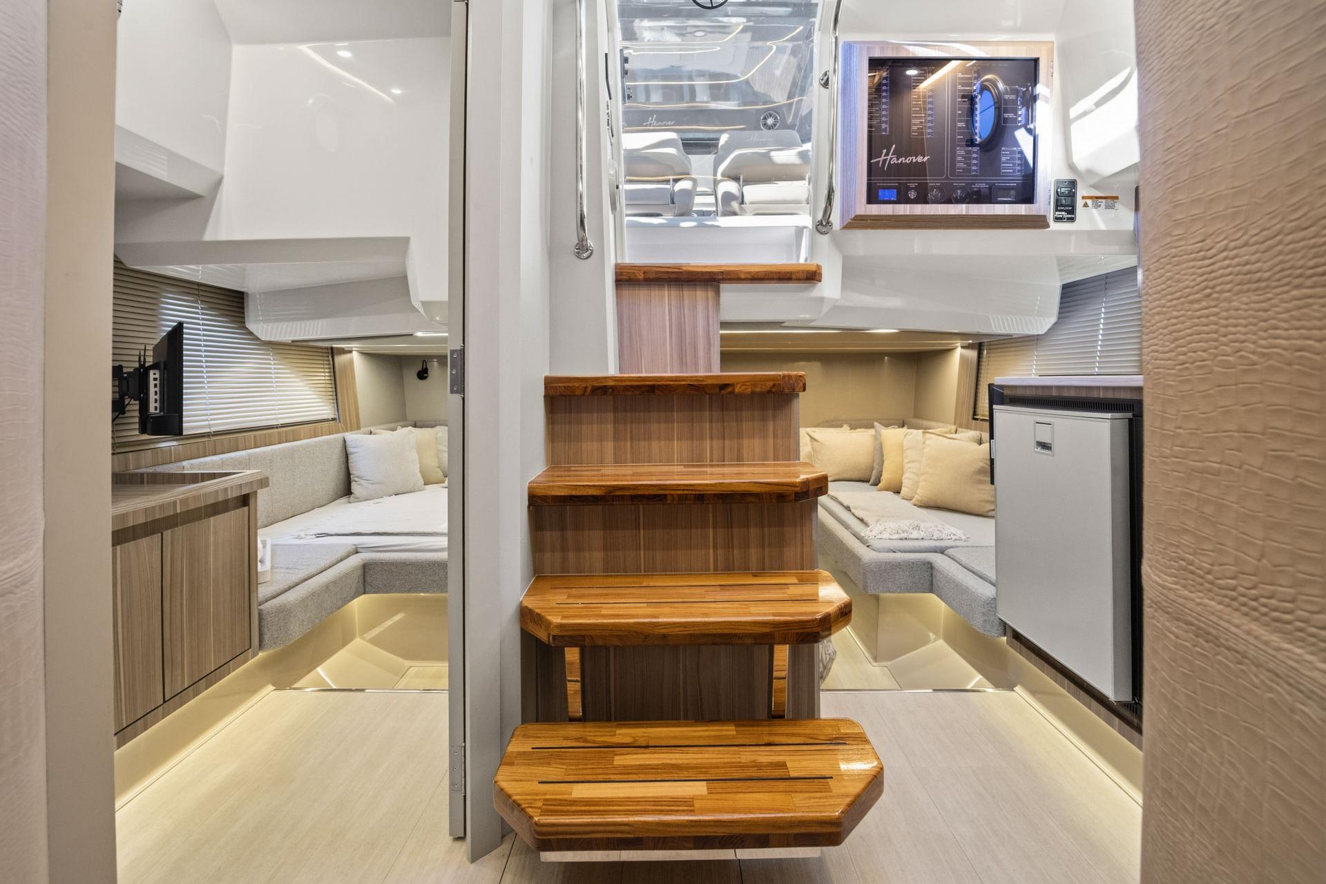 Luxurious interior of 2026 Hanover 447 yacht with wooden stairs and cozy seating area.