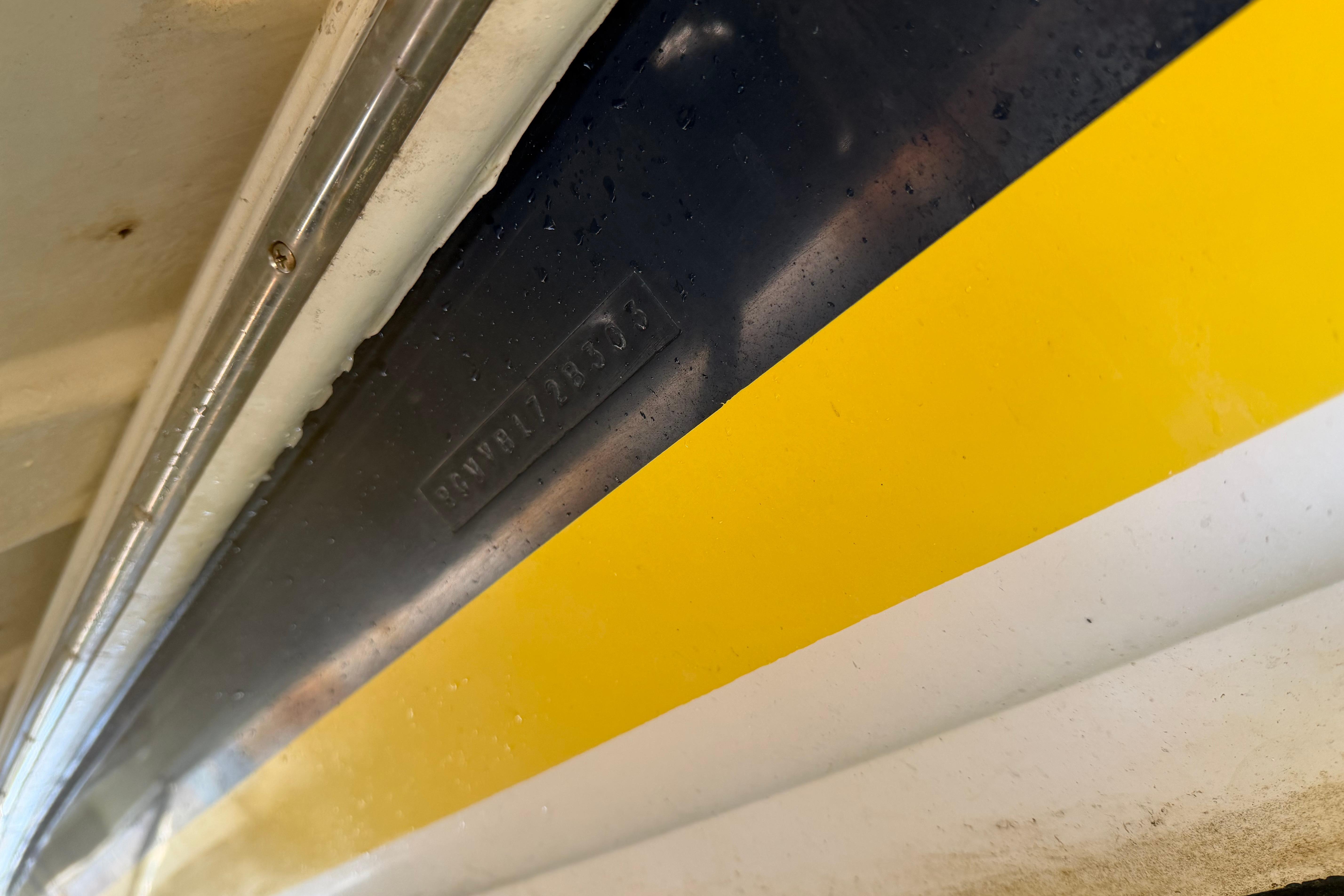 Close-up of a 2003 Regal Commodore 3260 boat hull with yellow and black stripes.
