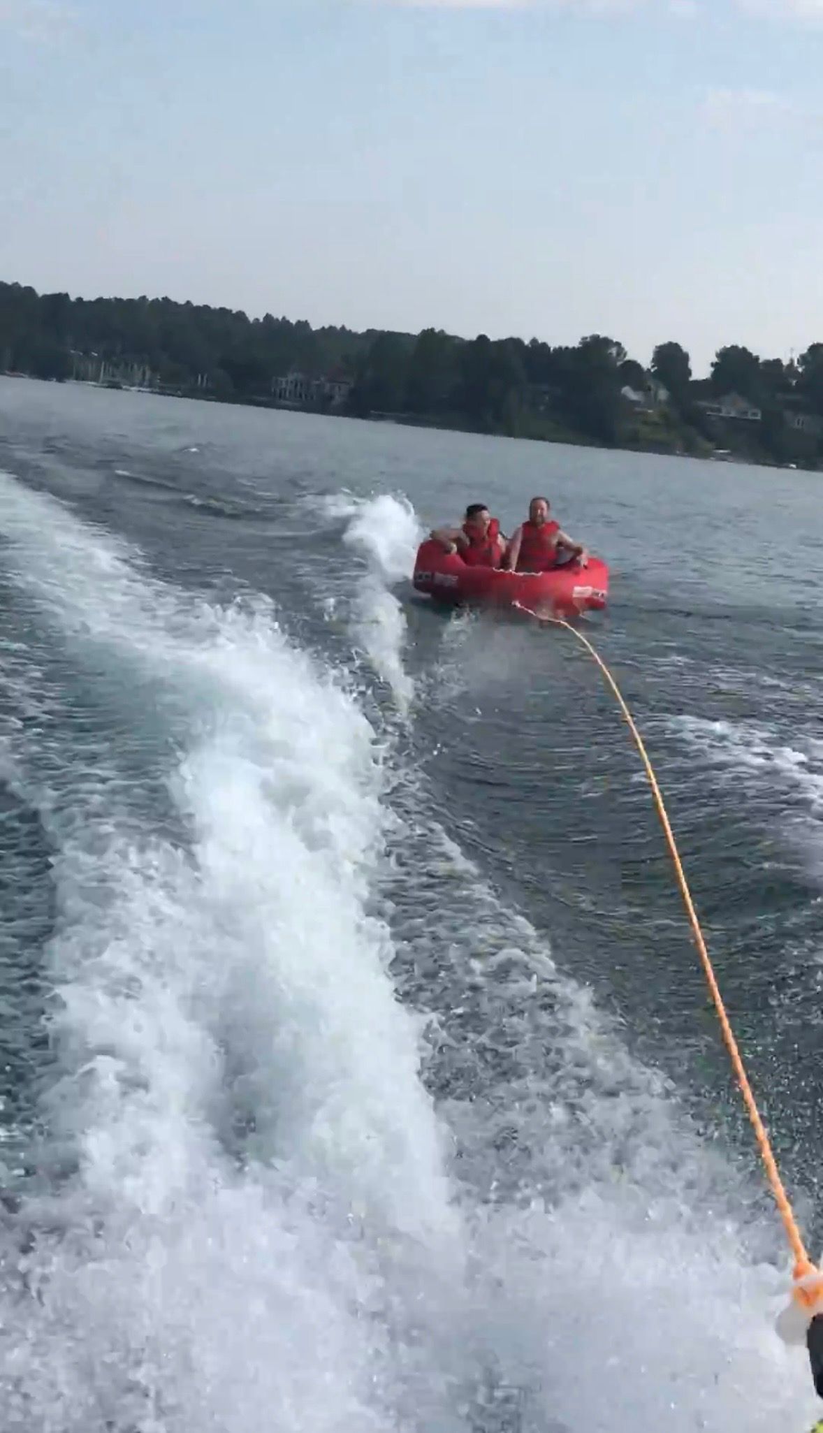 Two people tubing on a lake behind a boat.