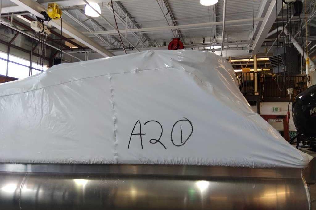 2025 Sun Tracker Party Barge 22 DLX covered in protective wrap inside a warehouse.