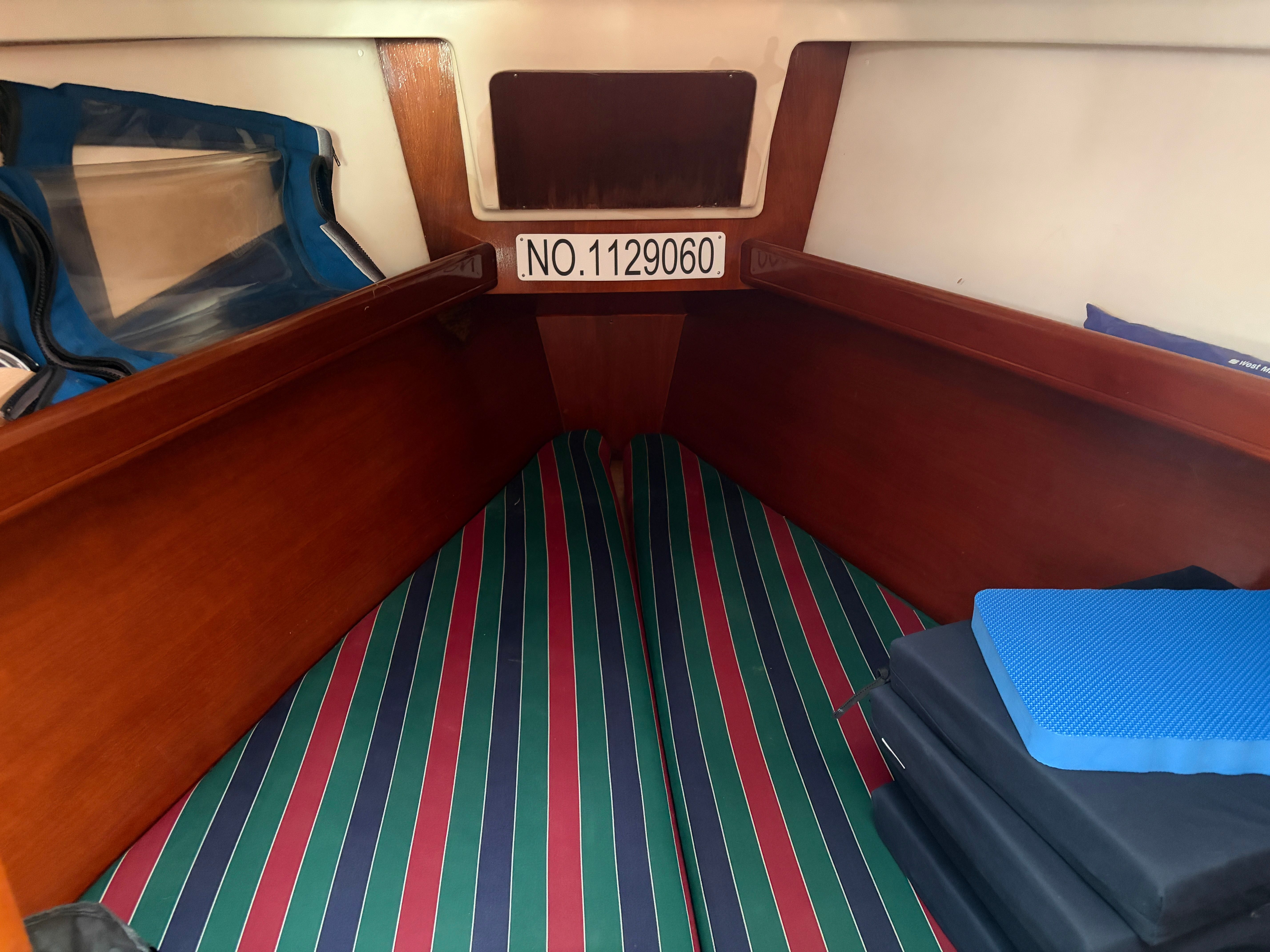 Interior of a 2000 Beneteau Oceanis 361 with striped cushions and storage space.