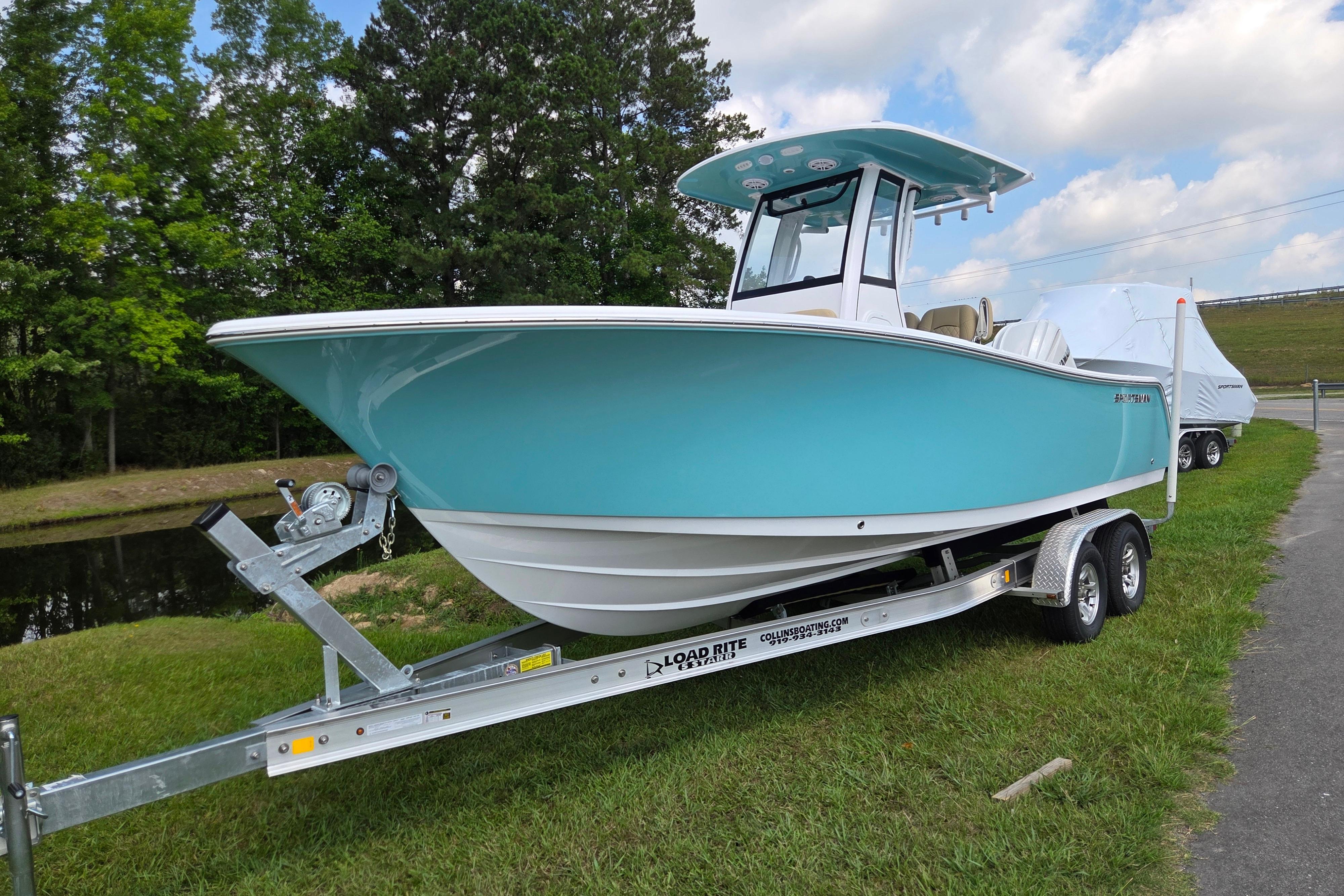 2026 Sportsman Open 232 Center Console boat on trailer, parked on grass.