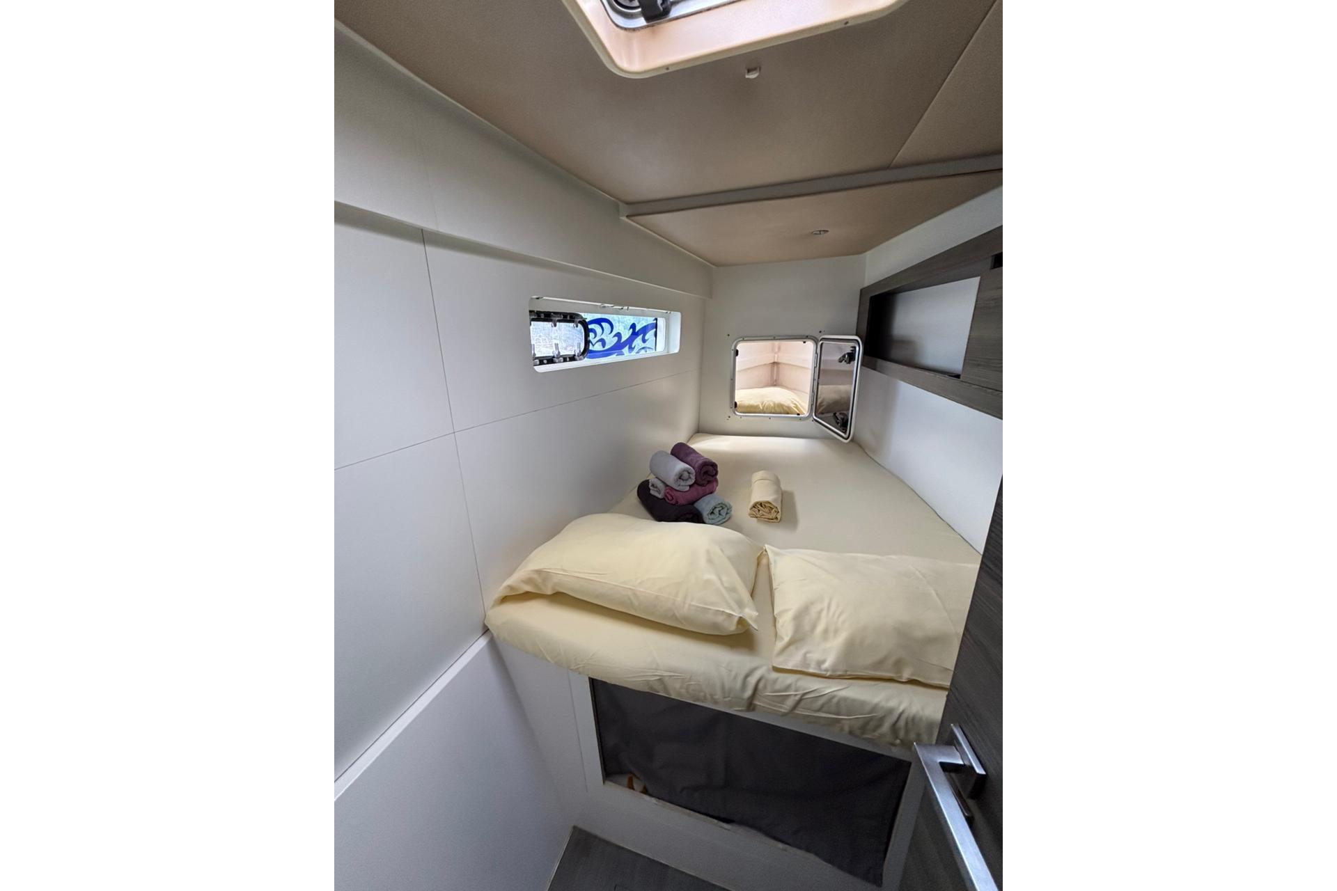 Cozy cabin interior of 2015 Nautitech 40 Open catamaran with bed and porthole.