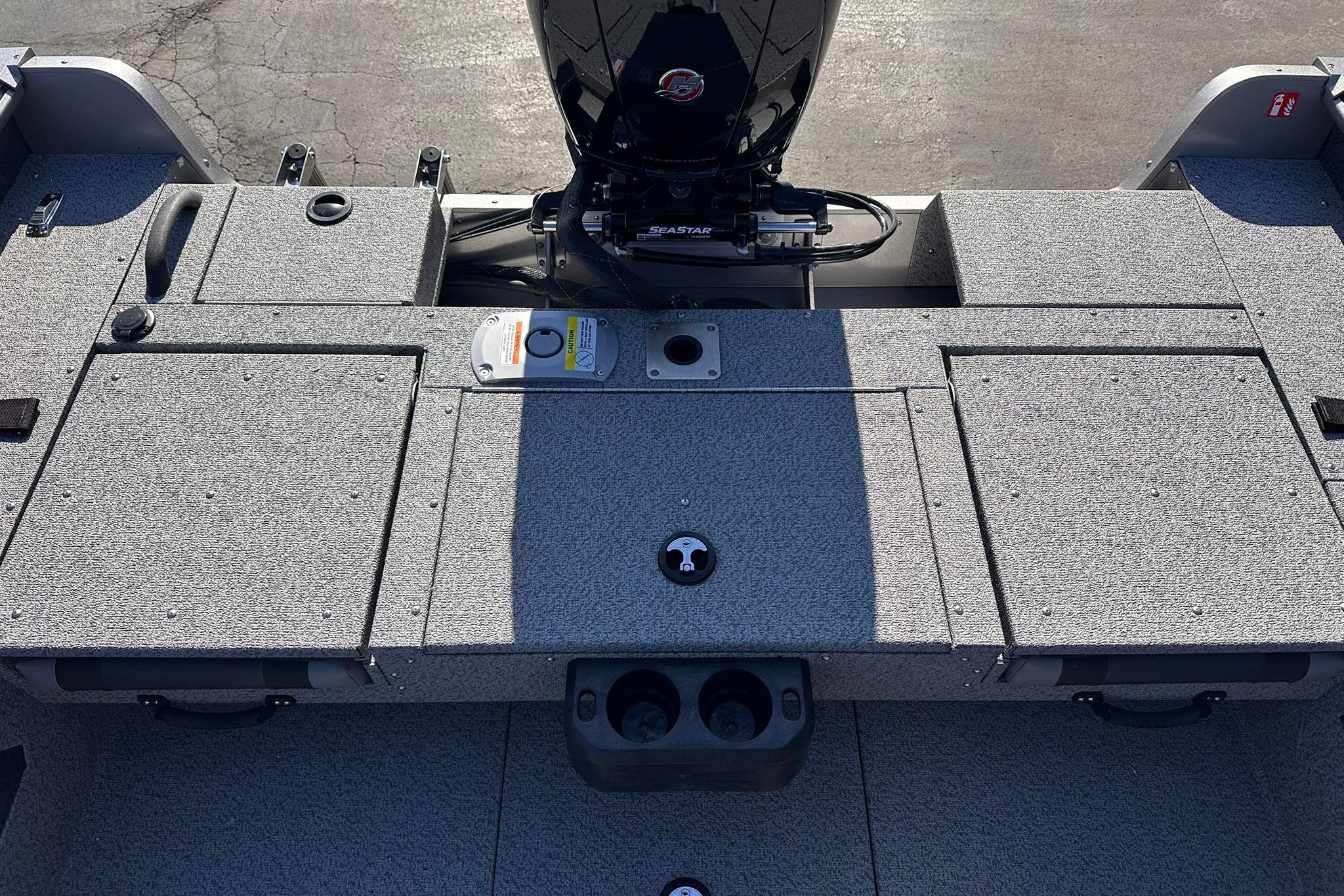 2026 Lund 1875 Impact XS SS boat deck with motor, featuring storage compartments.