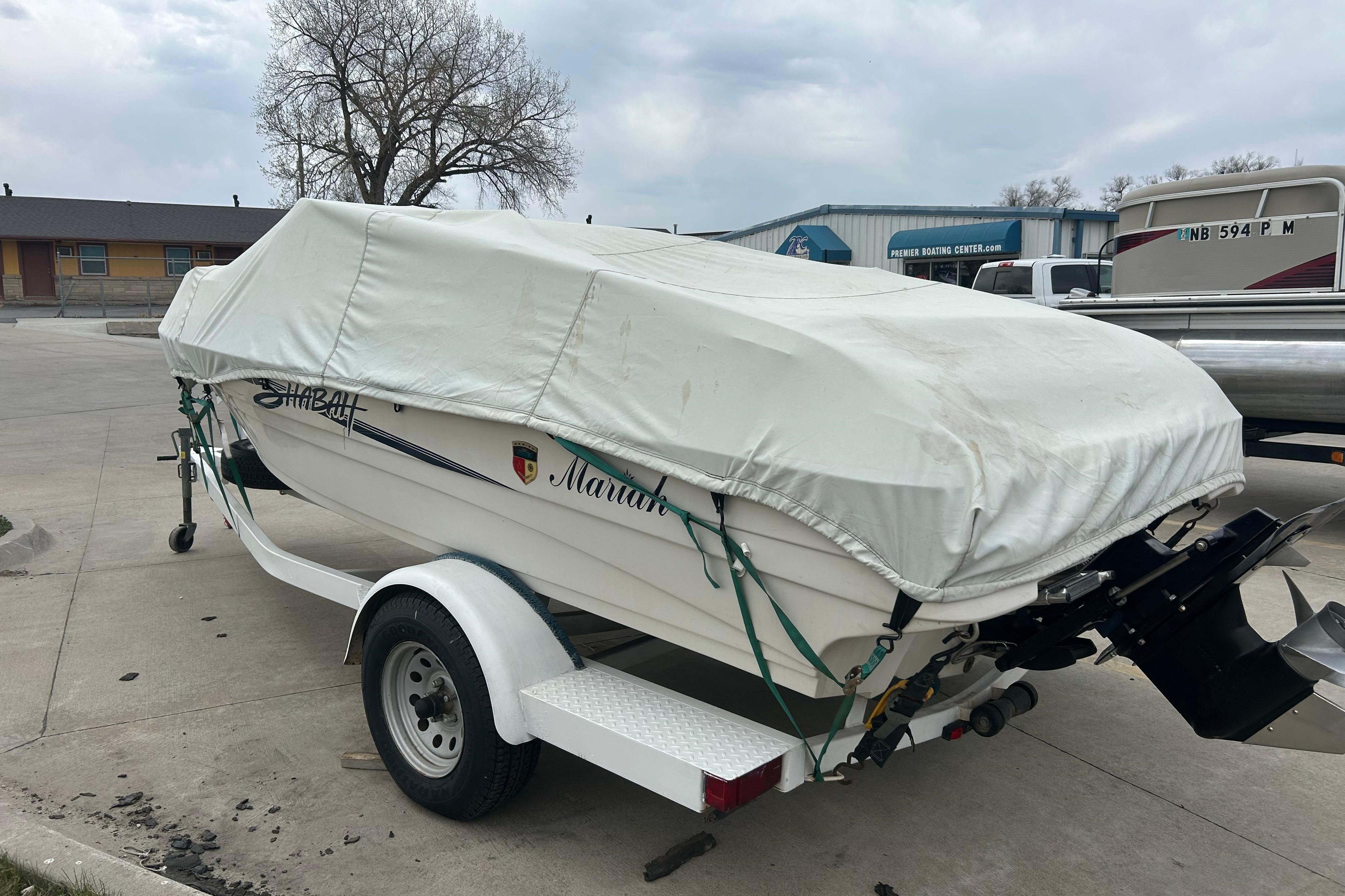 Covered 1996 Mariah 180 Shabah boat on trailer in parking lot.