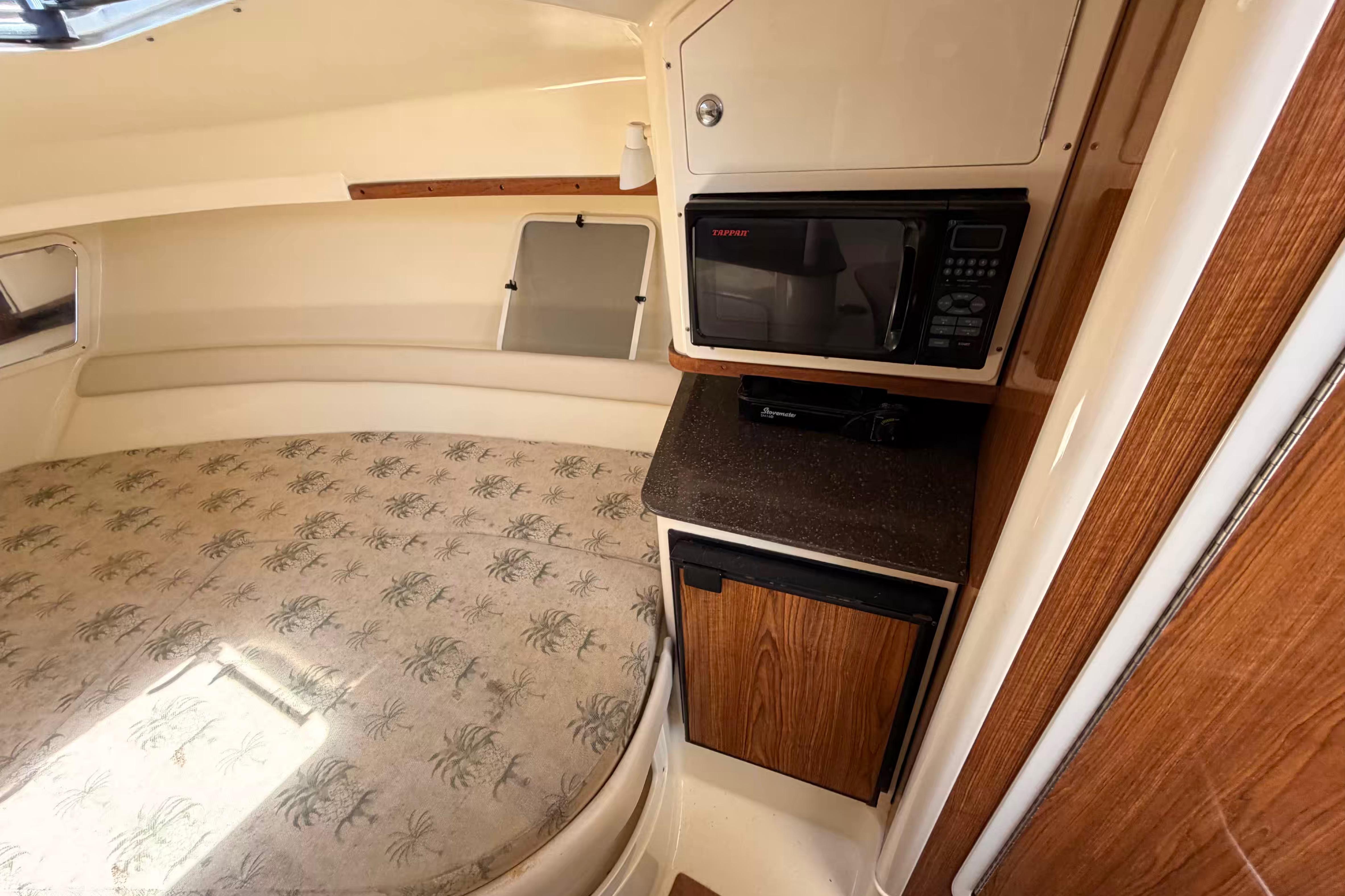 Interior of 2007 Scout 262 Abaco boat with bed, microwave, and mini-fridge.