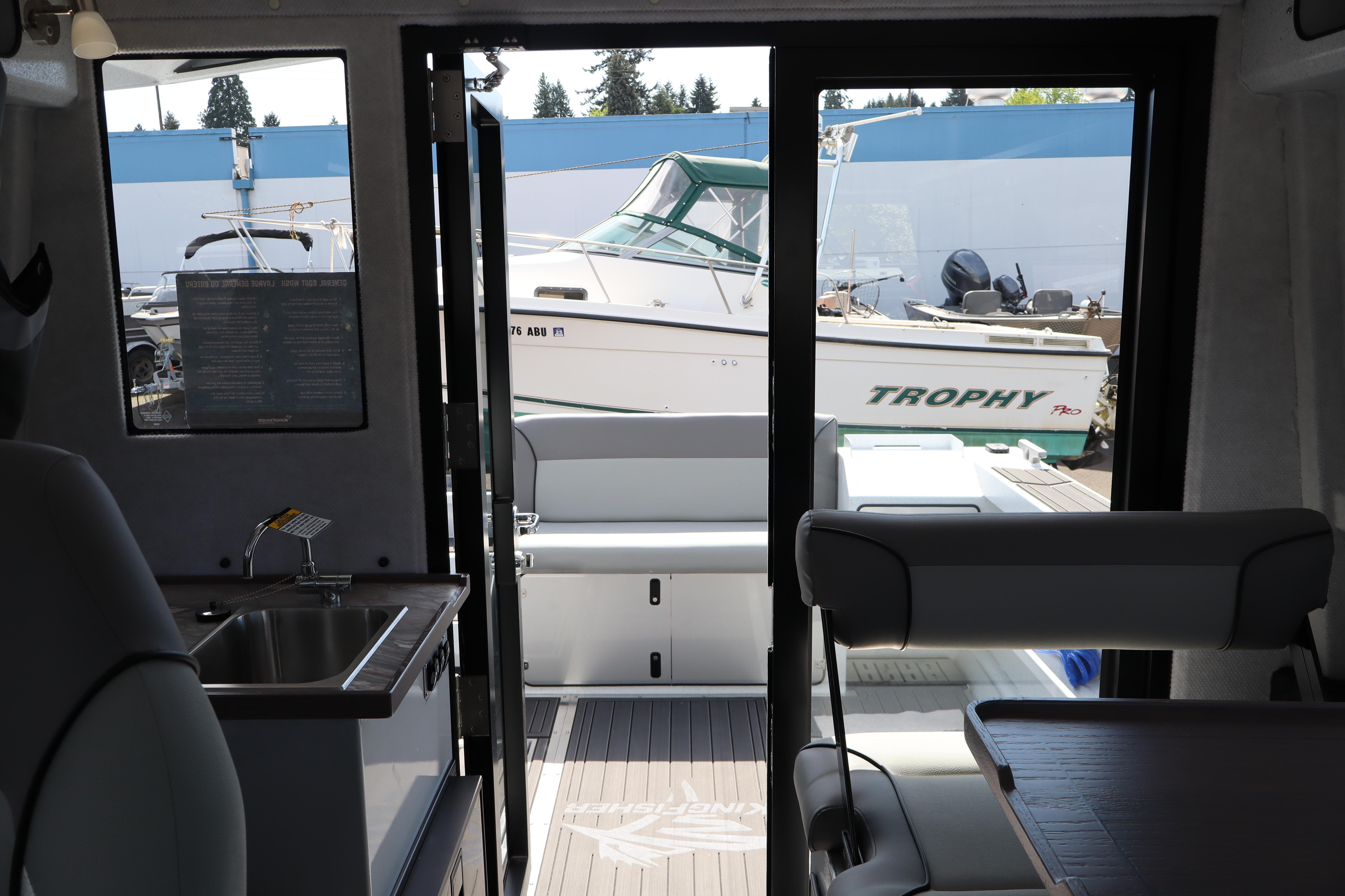 Interior view of 2026 KingFisher 25 XAC boat with outdoor marina scene.