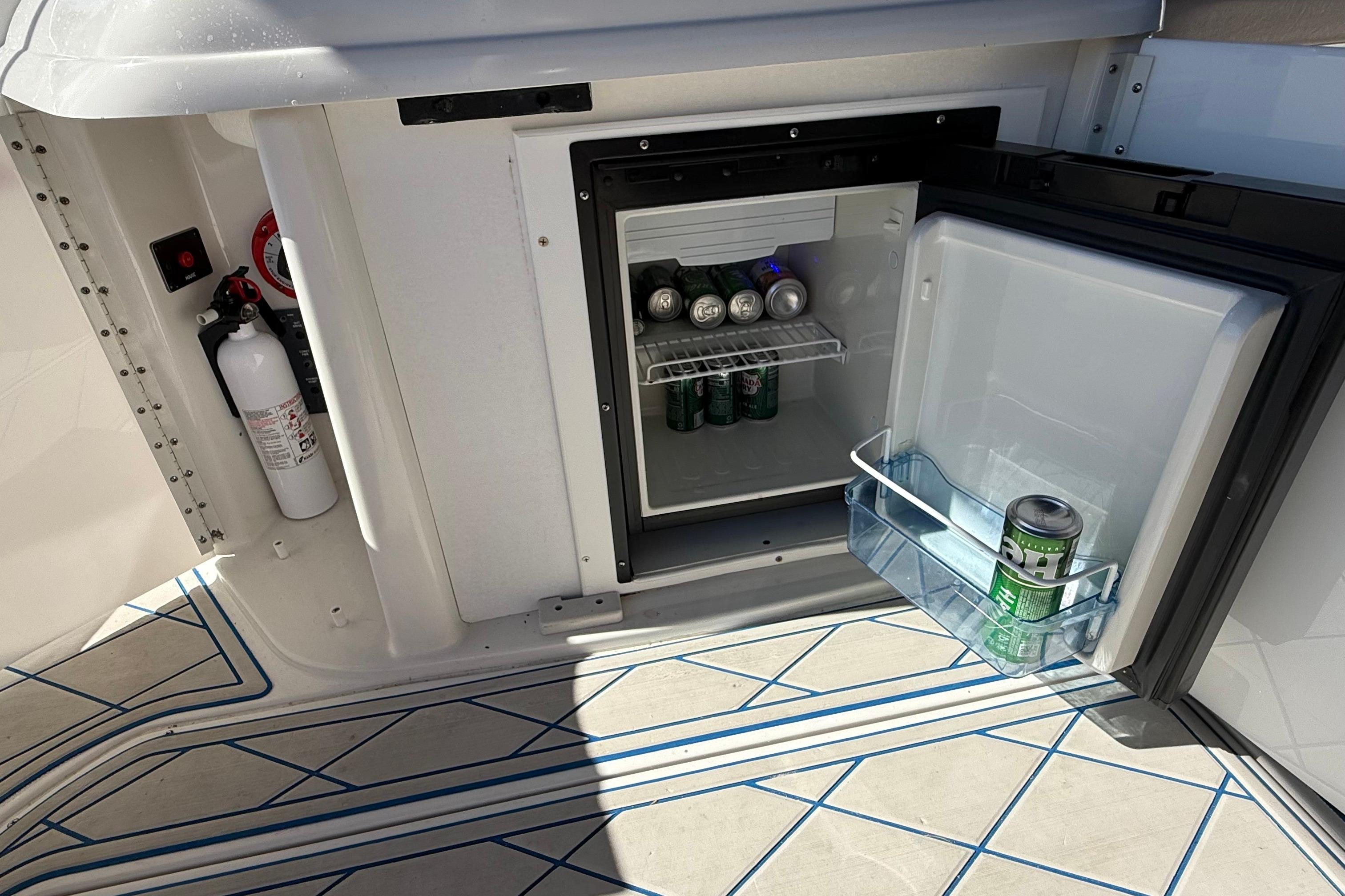 Open mini fridge on 1999 Formula 280 Sun Sport boat, stocked with canned drinks.