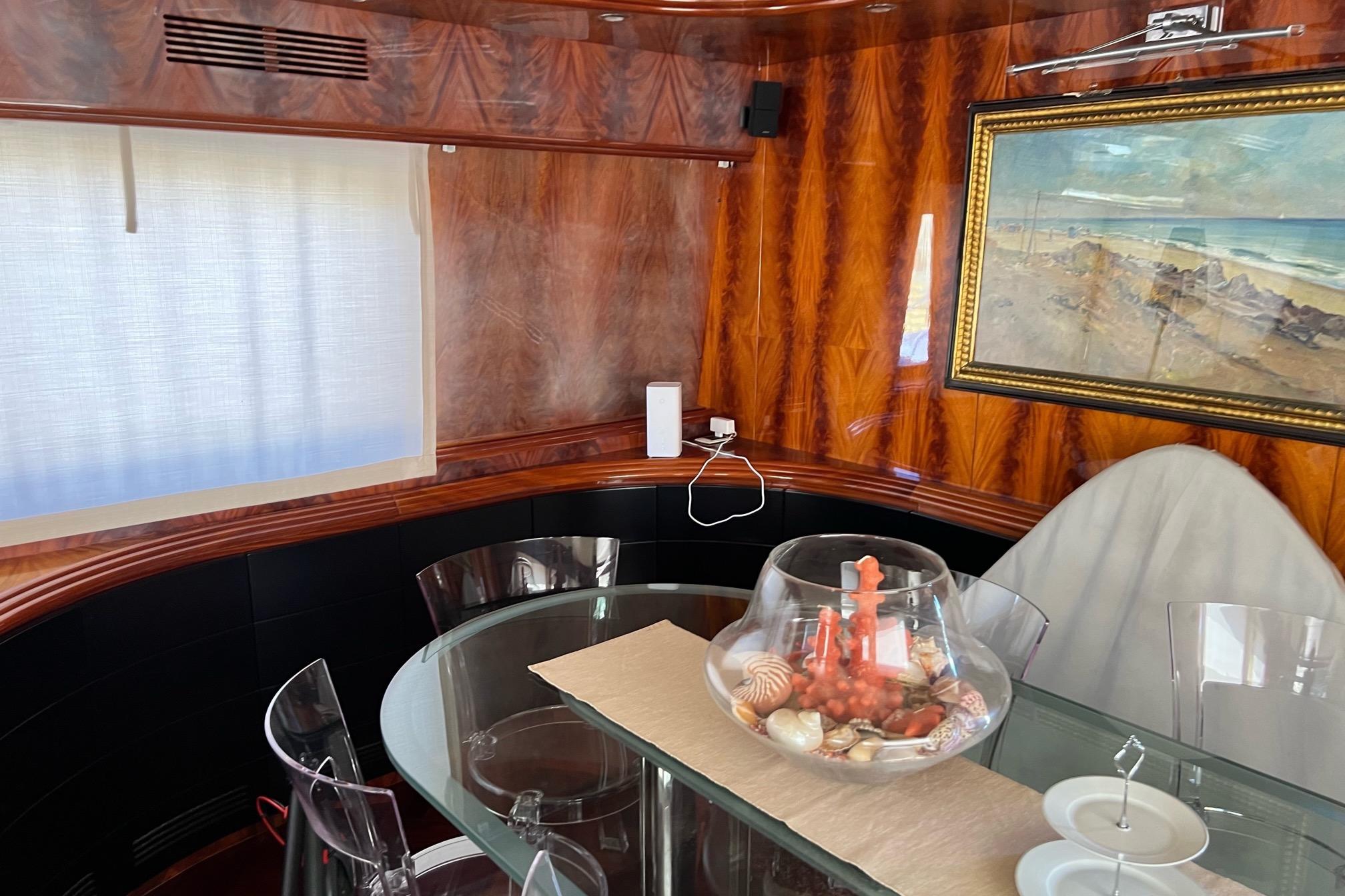 Luxurious Maiora 24 yacht interior with elegant wood paneling and glass dining table, 2001 model.