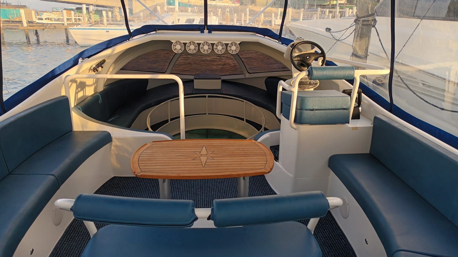 A modern boat with blue seating and a wooden table in an open area.