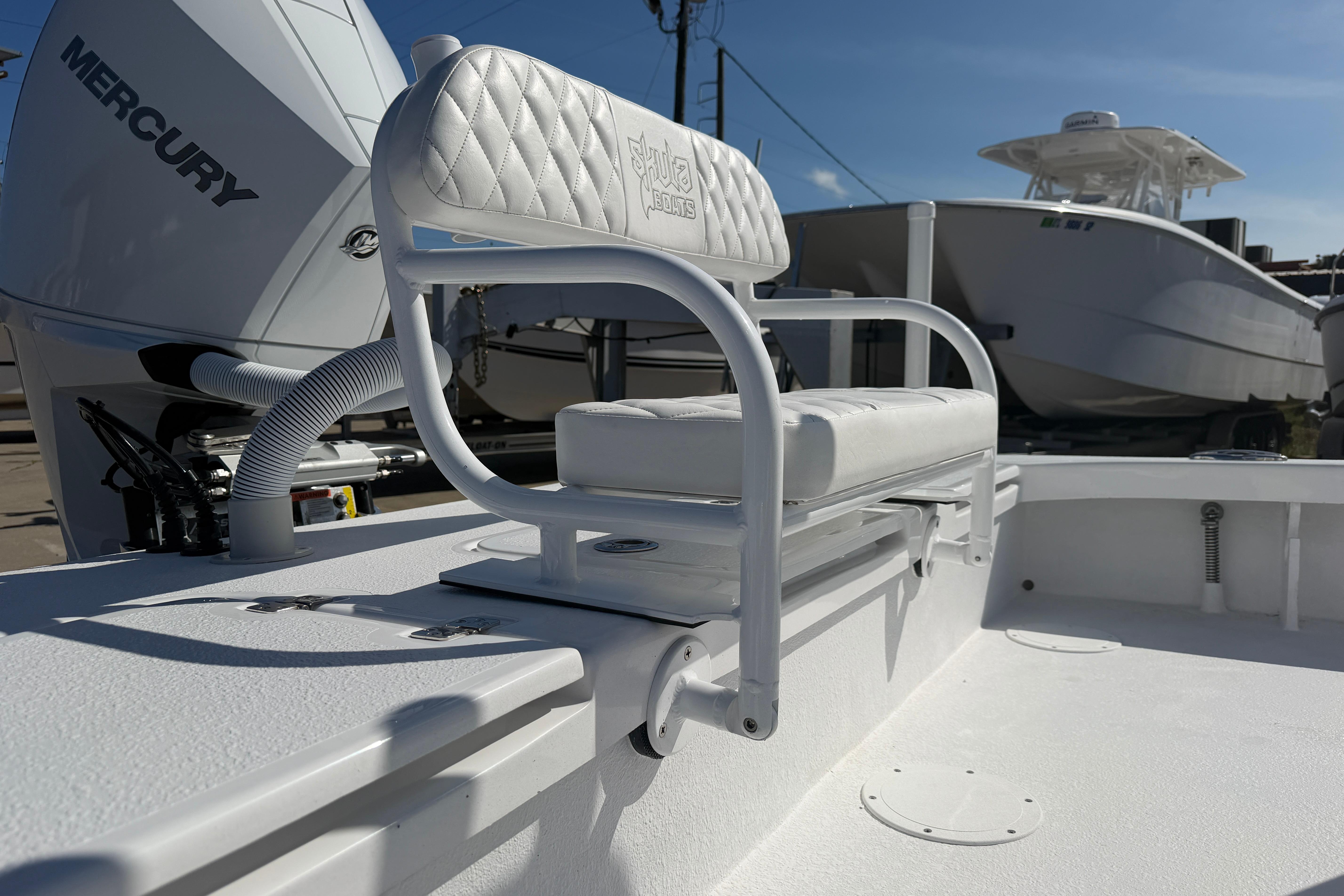 2026 Skuta 24 Cat boat with Mercury engine, featuring a white cushioned seat.