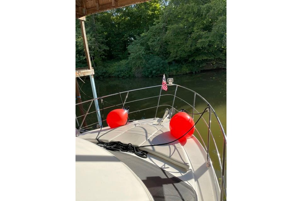 2003 Carver 36 Super Sport yacht with red buoys, docked near lush greenery.