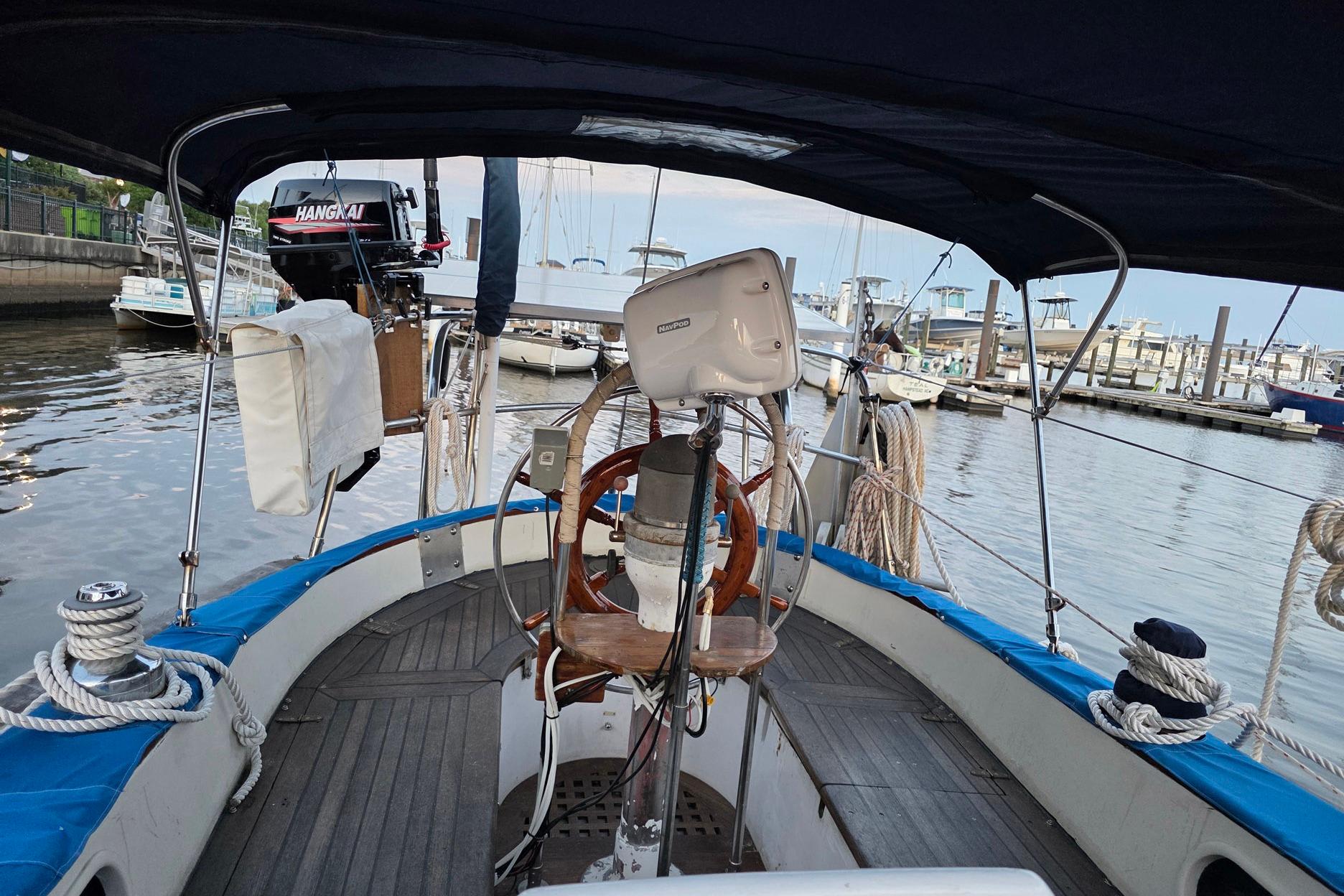1982 Tayana 37 sailboat cockpit with steering wheel, docked at marina.