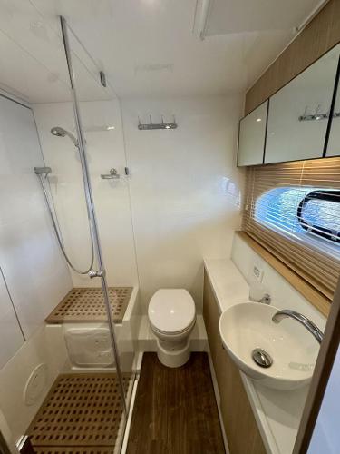 Modern bathroom in 2022 Aquila 44 yacht with shower, toilet, and sink.