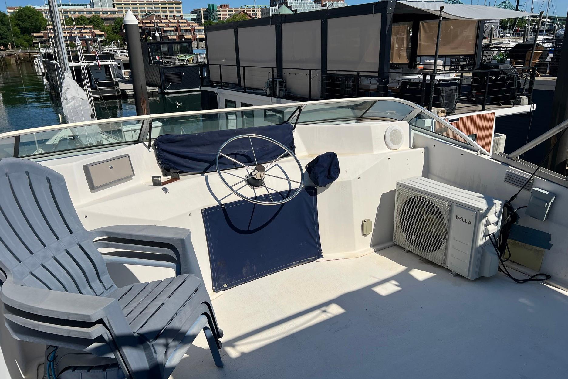 1993 Sumerset houseboat helm with steering wheel, chairs, and air conditioning unit at marina.