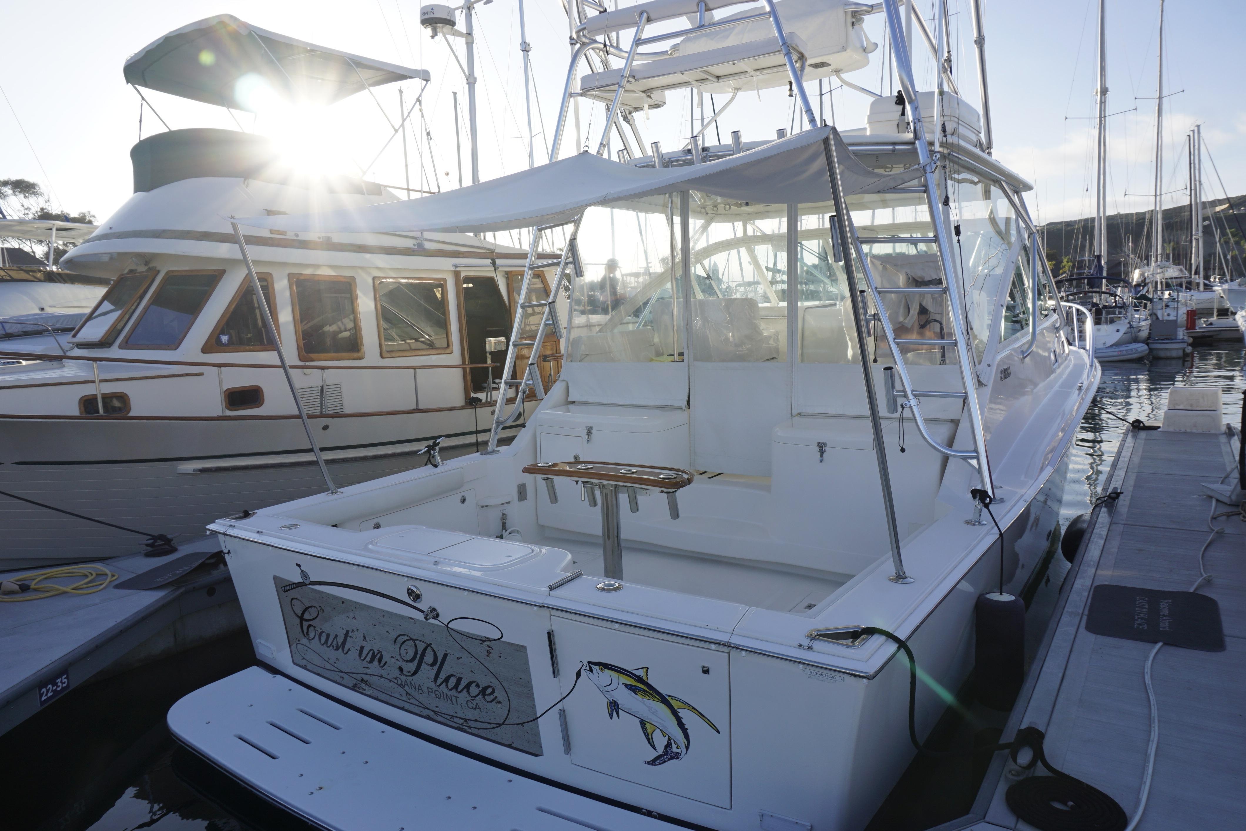 2005 Cabo 35 Express boat docked at marina with sunlit background.