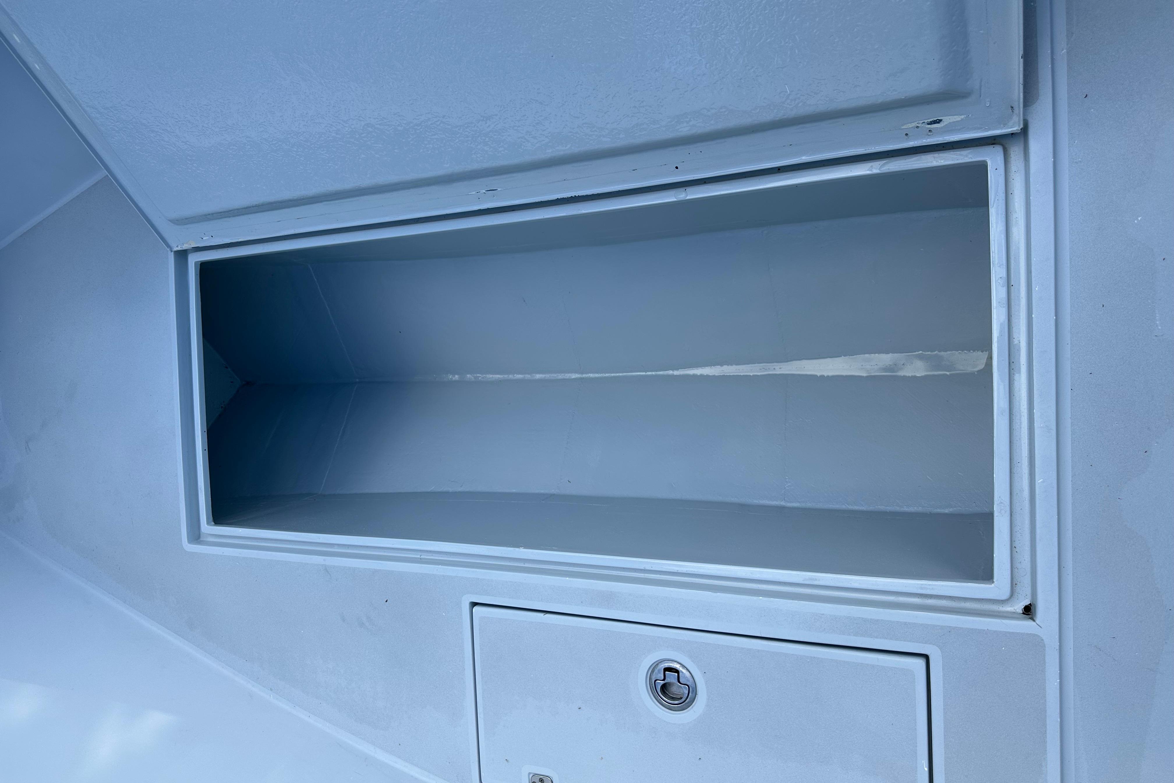 2004 SeaVee Center Console storage compartment with secure latch, open and empty.