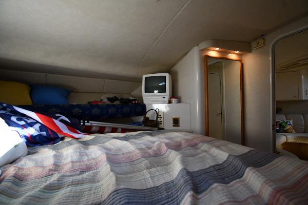 Interior cabin of 1997 Sea Ray 400 Sundancer with bed, TV, and cozy decor.
