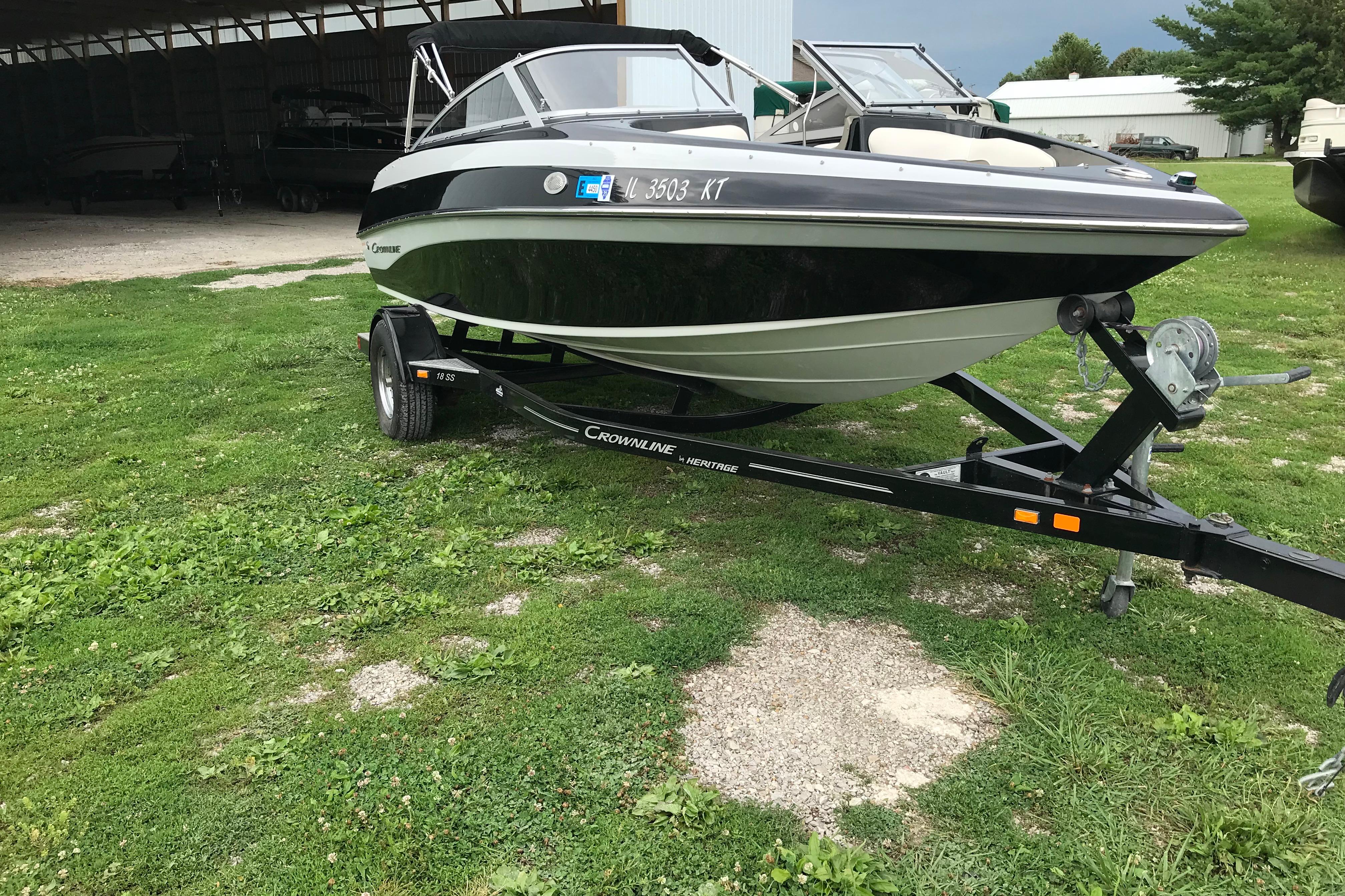 2015 Crownline 18 SS boat on trailer, parked on grass near a storage building.
