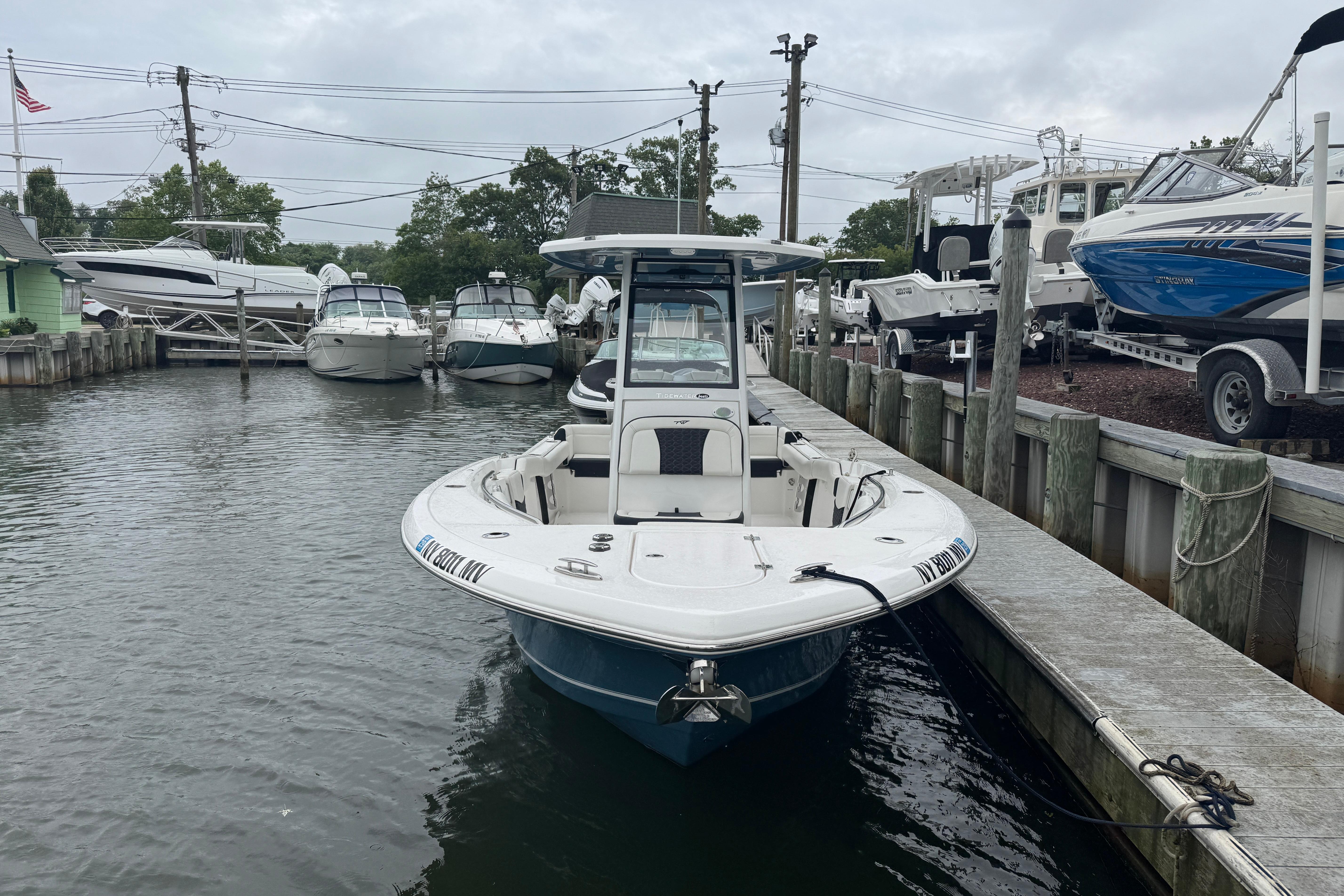 2025 Tidewater 232 LXF boat docked in a marina, surrounded by other vessels.