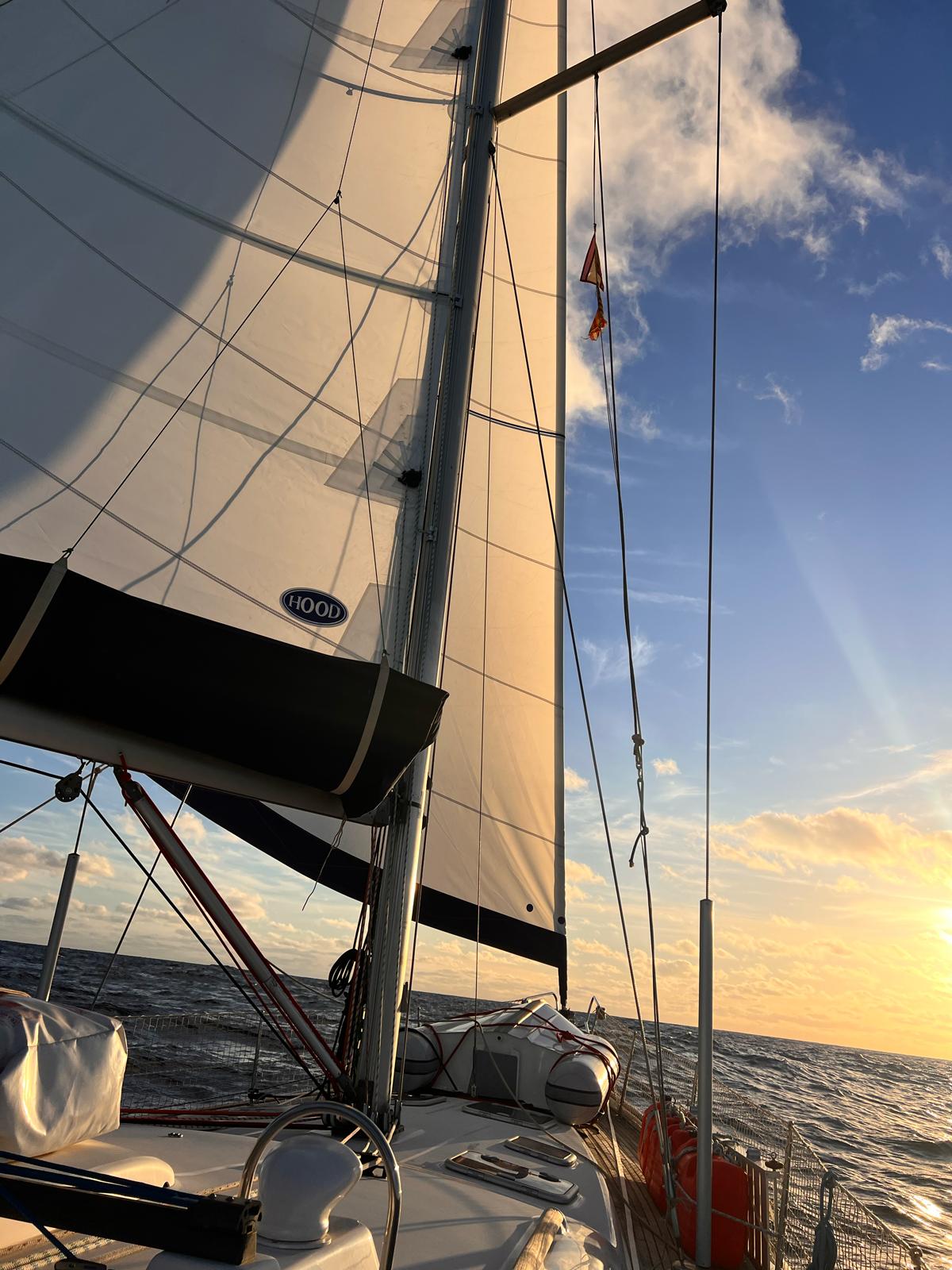 Sailing on a 2006 Beneteau Oceanis 473 at sunset, open sea view.