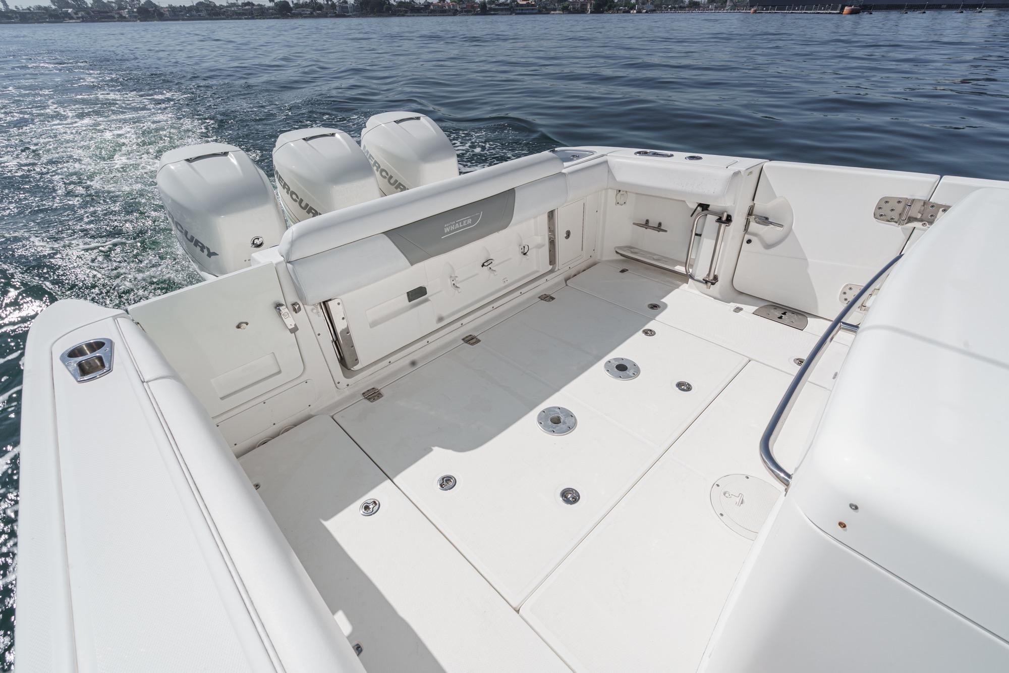 2015 Boston Whaler 370 Outrage boat deck with triple Mercury engines on water.