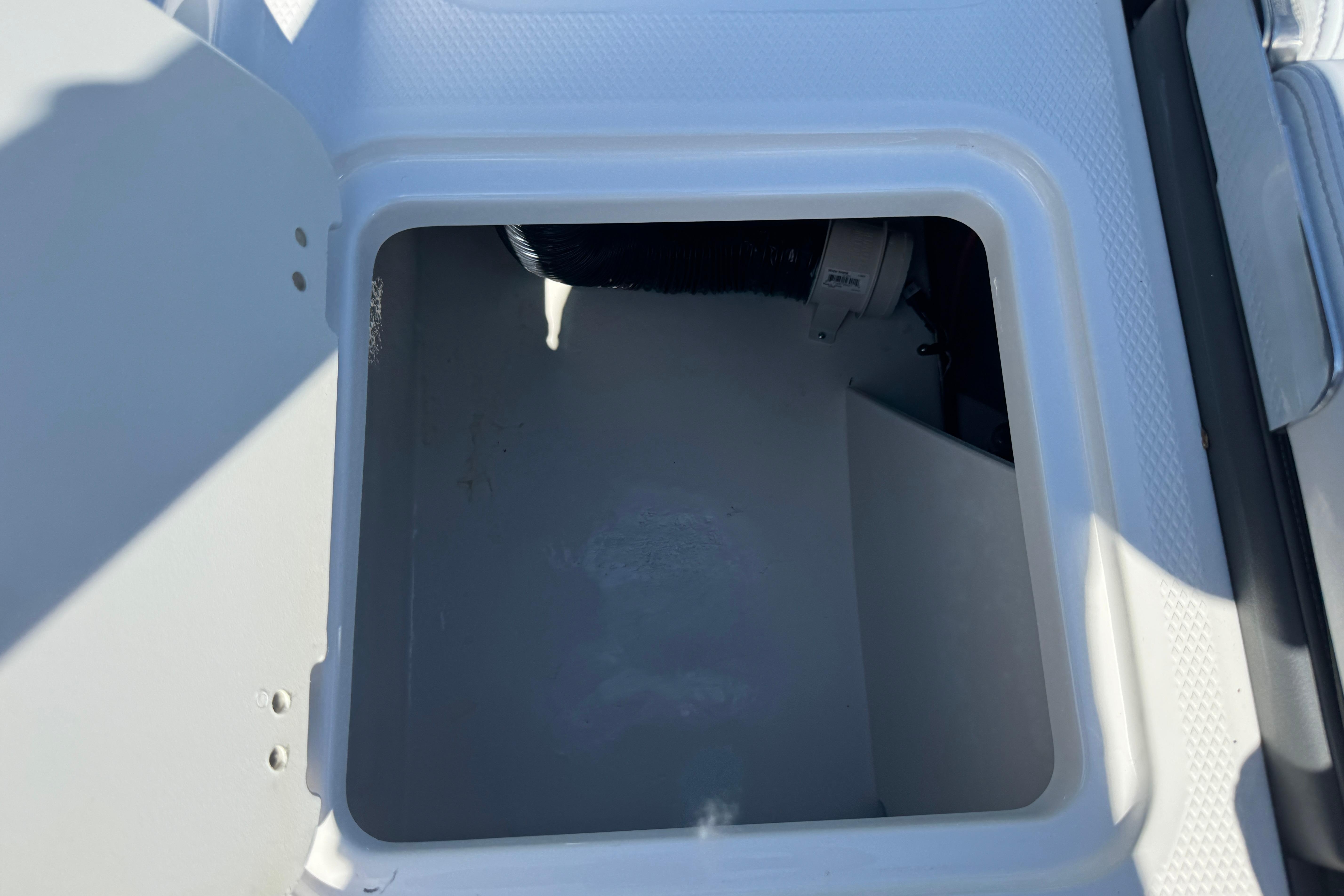 Storage compartment of 2026 Chaparral 21 SSi boat, open and empty.