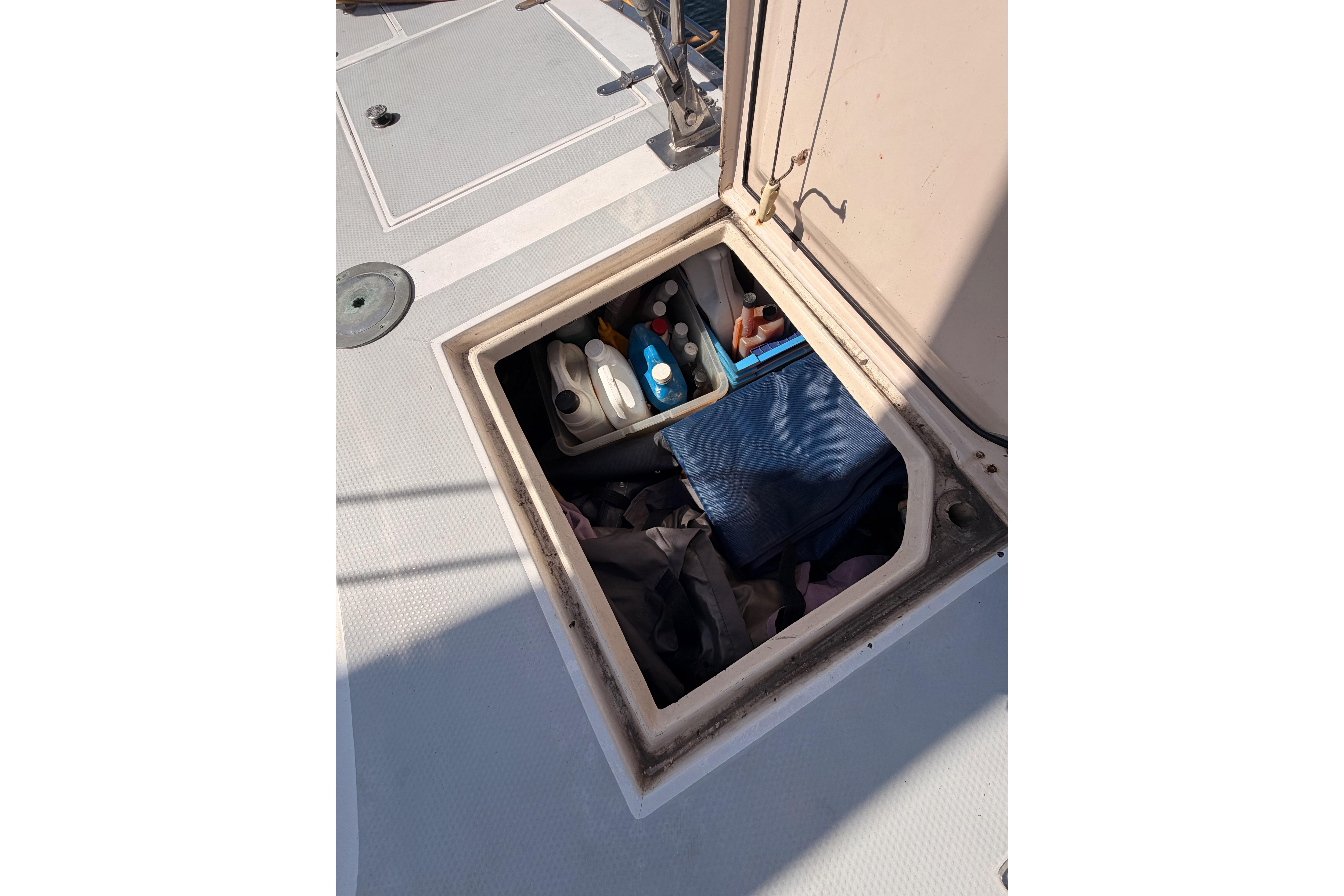 Open storage compartment on 1991 Hylas 51 yacht deck with various supplies.
