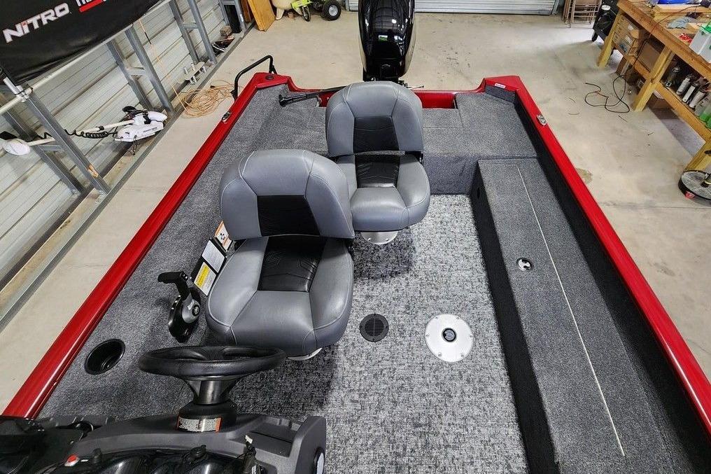 2026 Tracker Super Guide V-16 SC boat interior with gray seats and red trim in a garage.