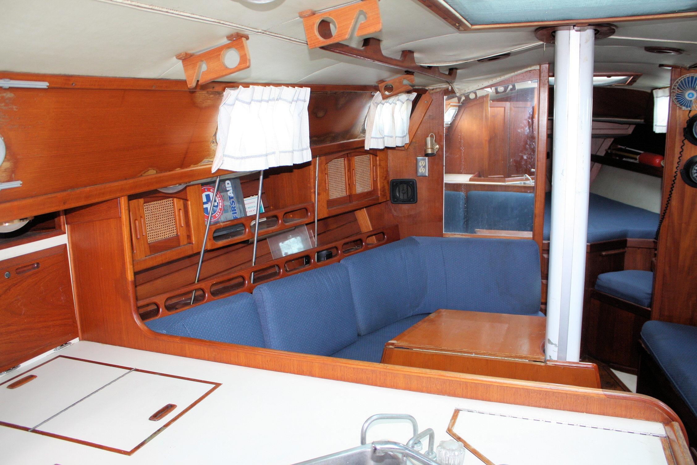 Interior of 1987 Ericson 38-200 sailboat with wooden cabinetry and blue seating.