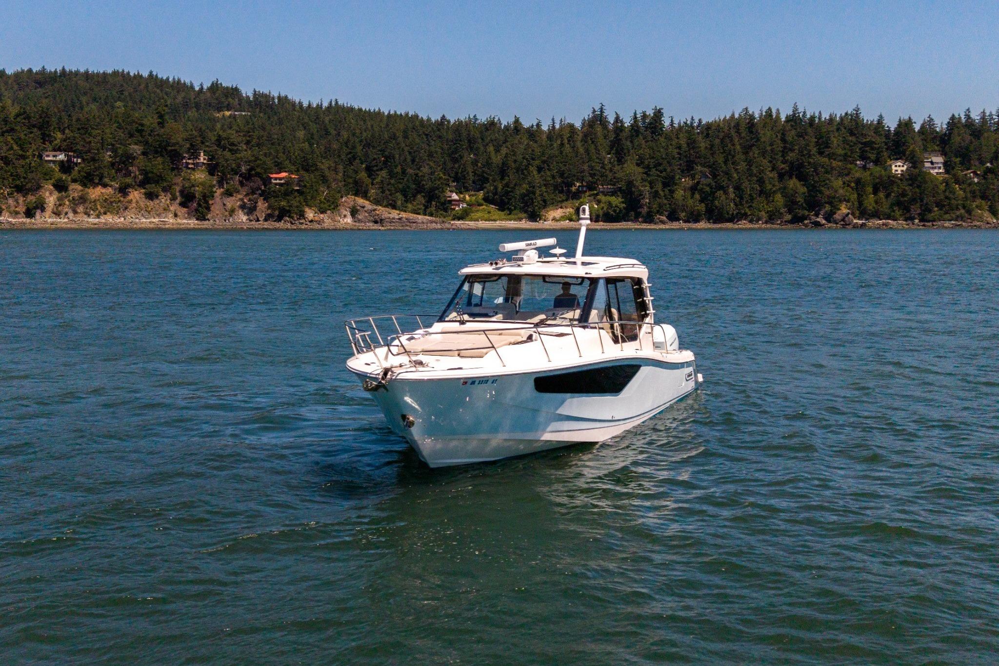 2023 Boston Whaler 405 Conquest cruising on a scenic lake with forested shoreline.