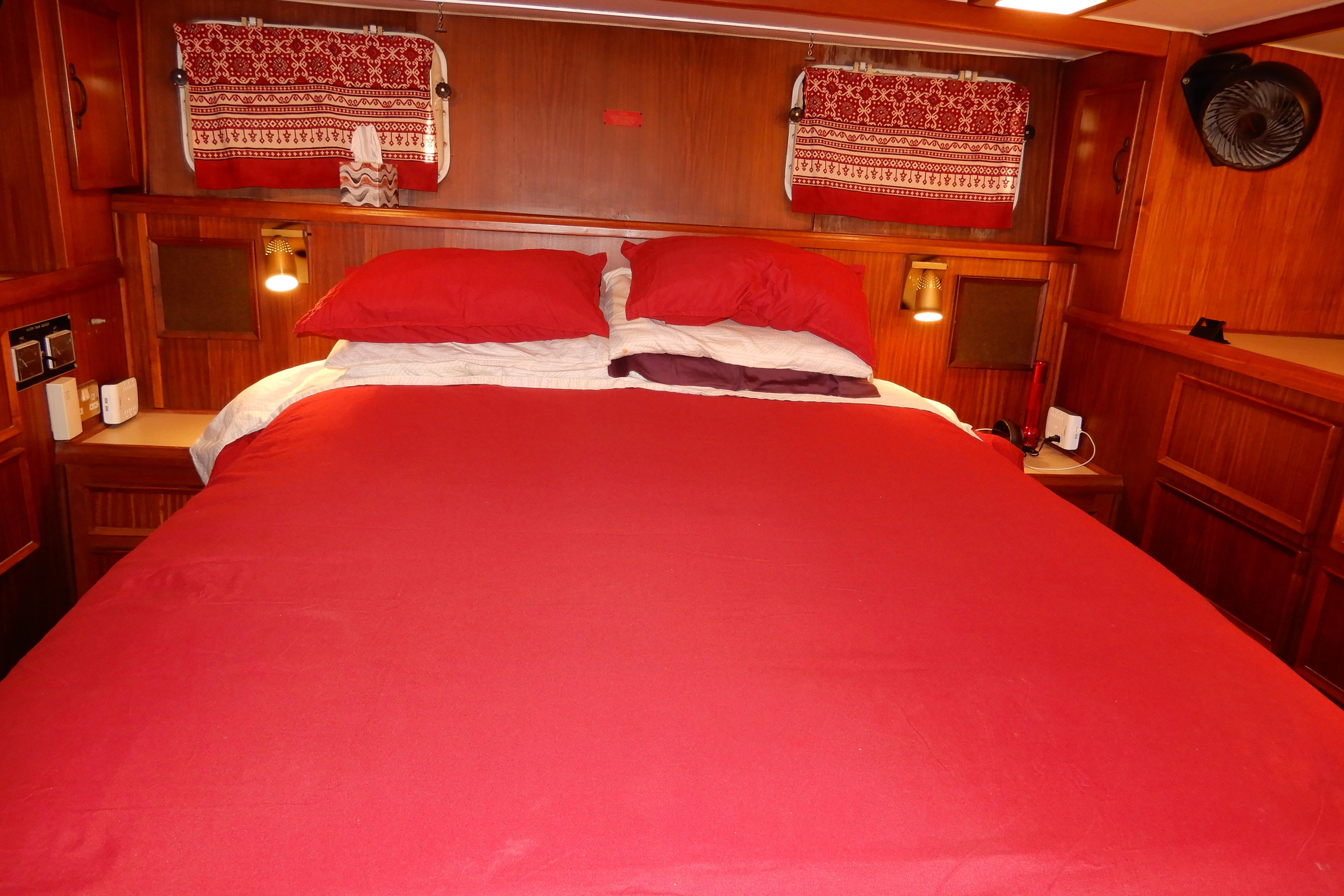 Cozy bedroom with red bedding in 1979 Hatteras 53 Motor Yacht cabin.