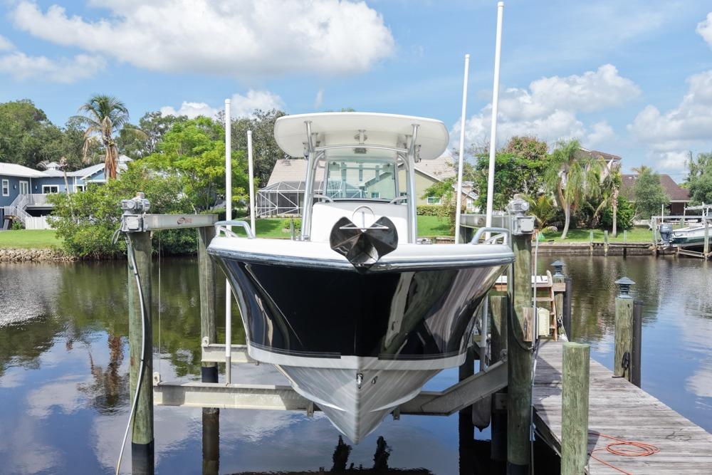 2018 Mako 284 Center Console boat docked on a lift by a scenic waterfront.