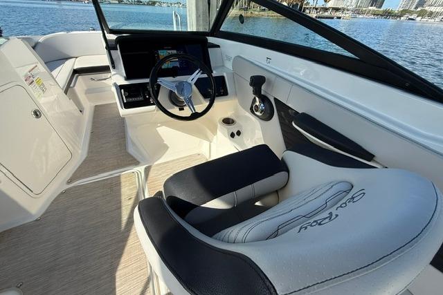 2022 Sea Ray SPX 210 Outboard boat interior with steering wheel and seating, docked by the water.