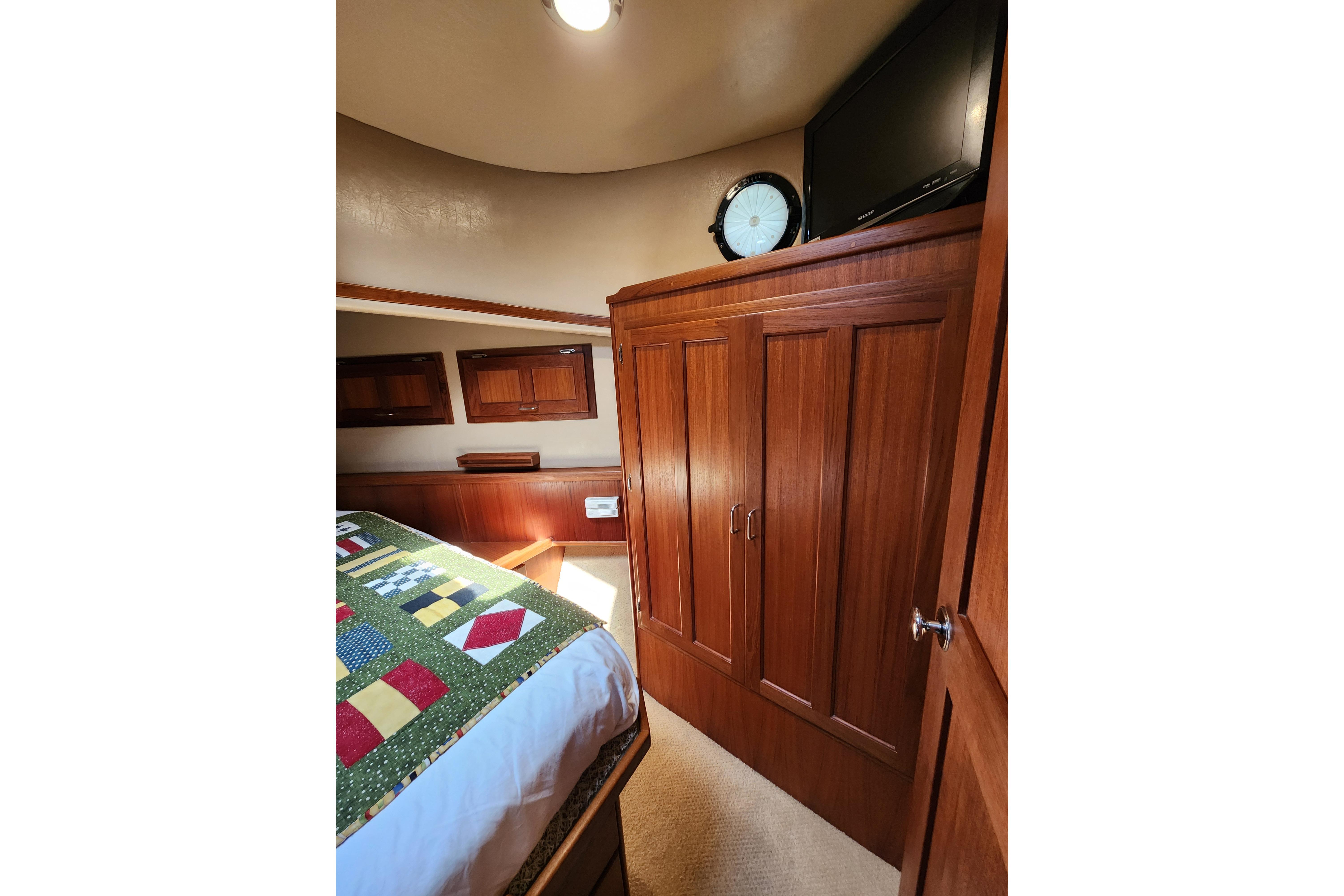 Cozy cabin interior of 2006 American Tug AT with wooden cabinetry and colorful quilted bedspread.