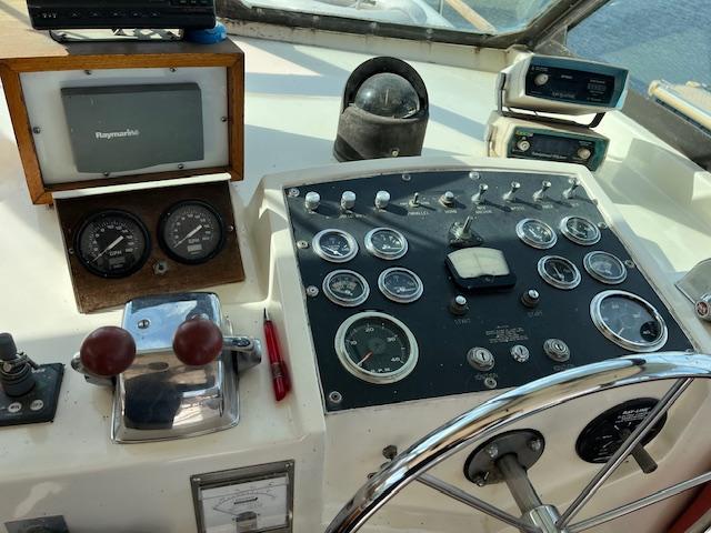 1977 Hatteras 43 Double Cabin helm with gauges, steering wheel, and navigation equipment.