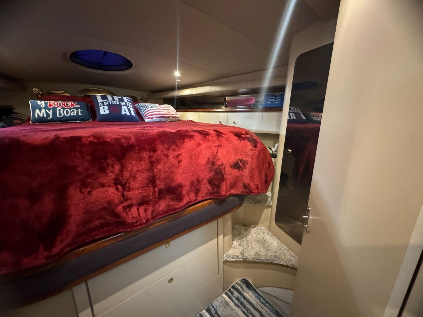Cozy cabin interior of 2000 Cruisers Yachts 4270 Express with red bedding and nautical decor.