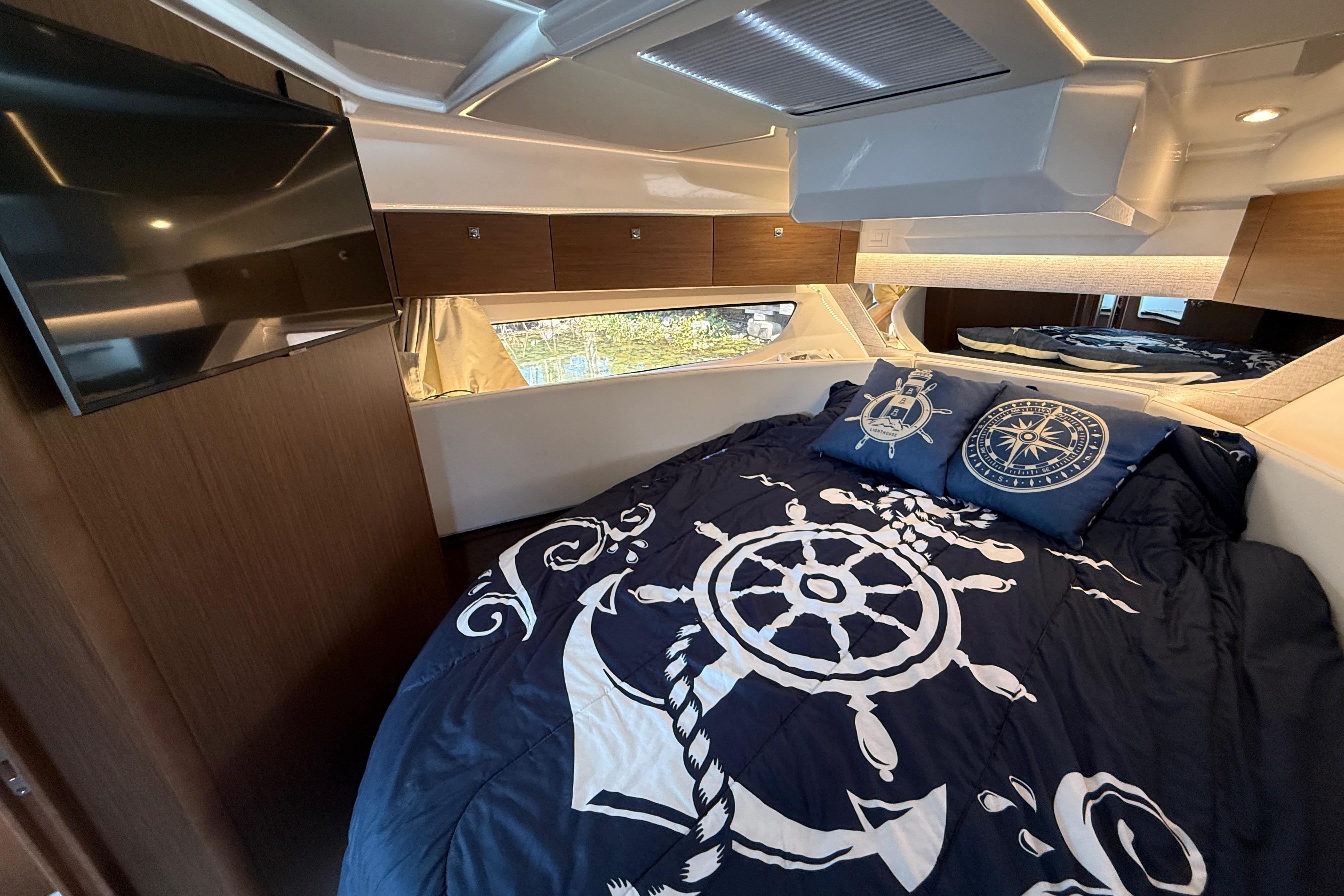 Luxurious cabin interior of 2022 Jeanneau NC 1095 Fly with nautical-themed bedding.