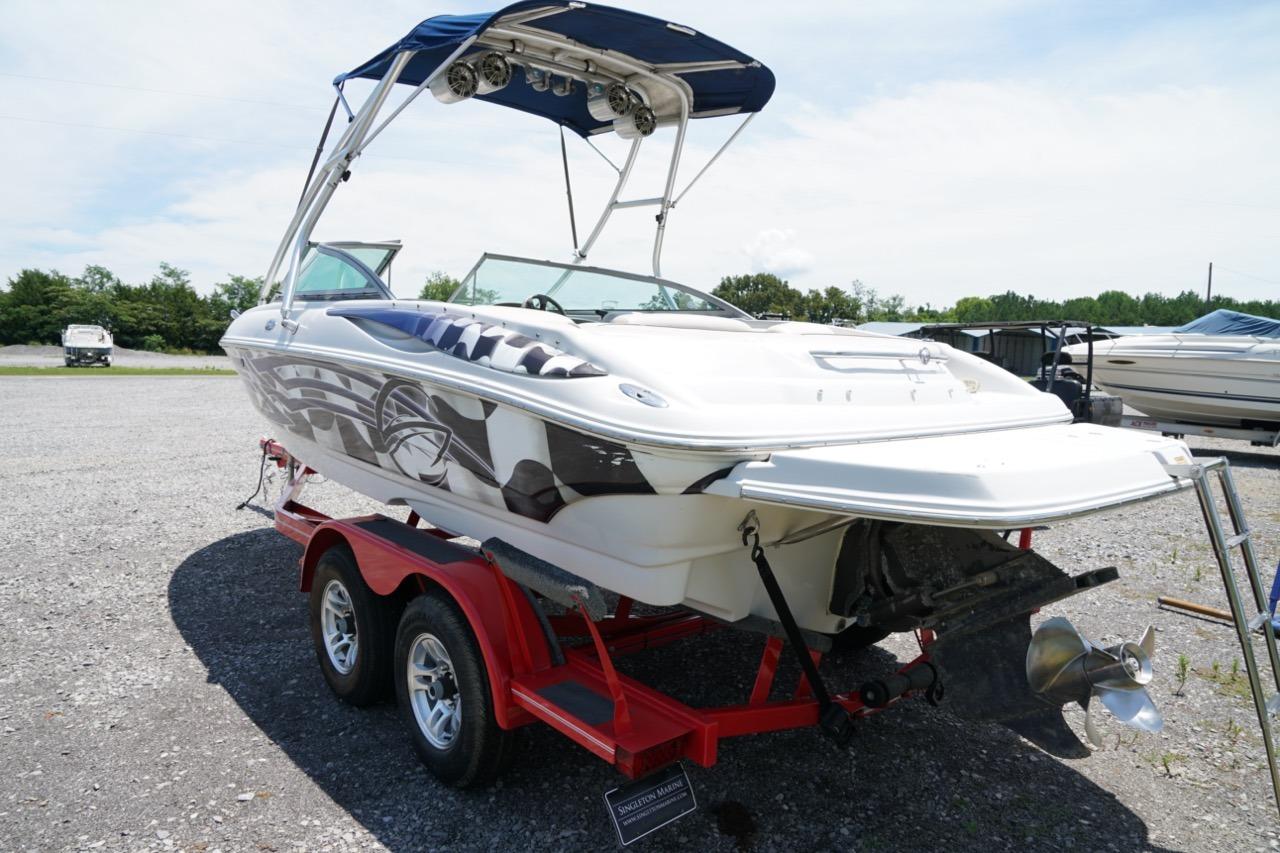 2004 Crownline 216 LS boat on red trailer, parked outdoors under clear sky.