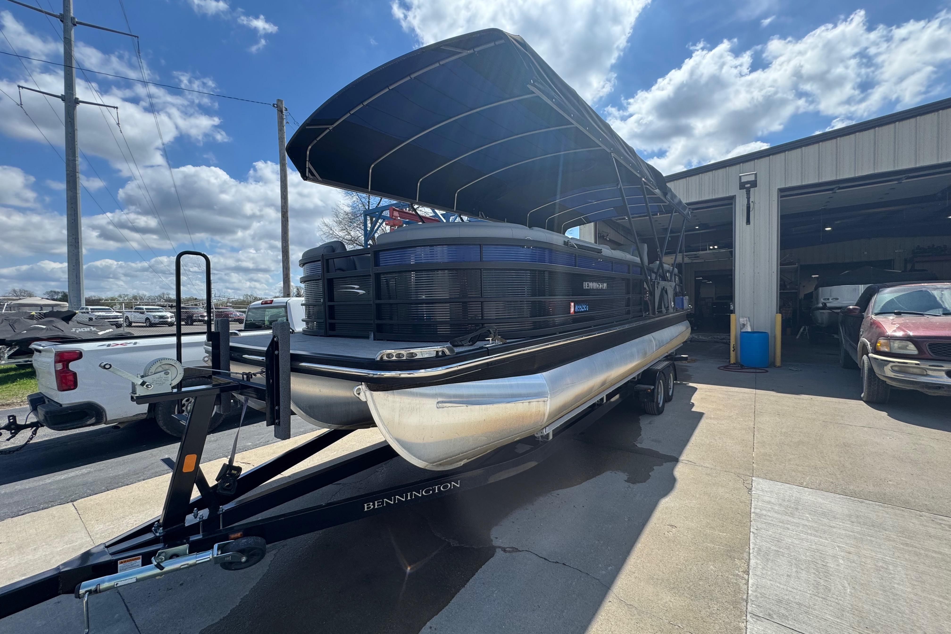 2020 Bennington R 25 RFB pontoon boat on trailer, parked outside a garage.