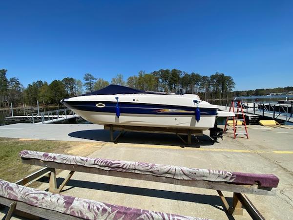2005 Bayliner 249 SD boat on a trailer, dockside, under clear blue sky.