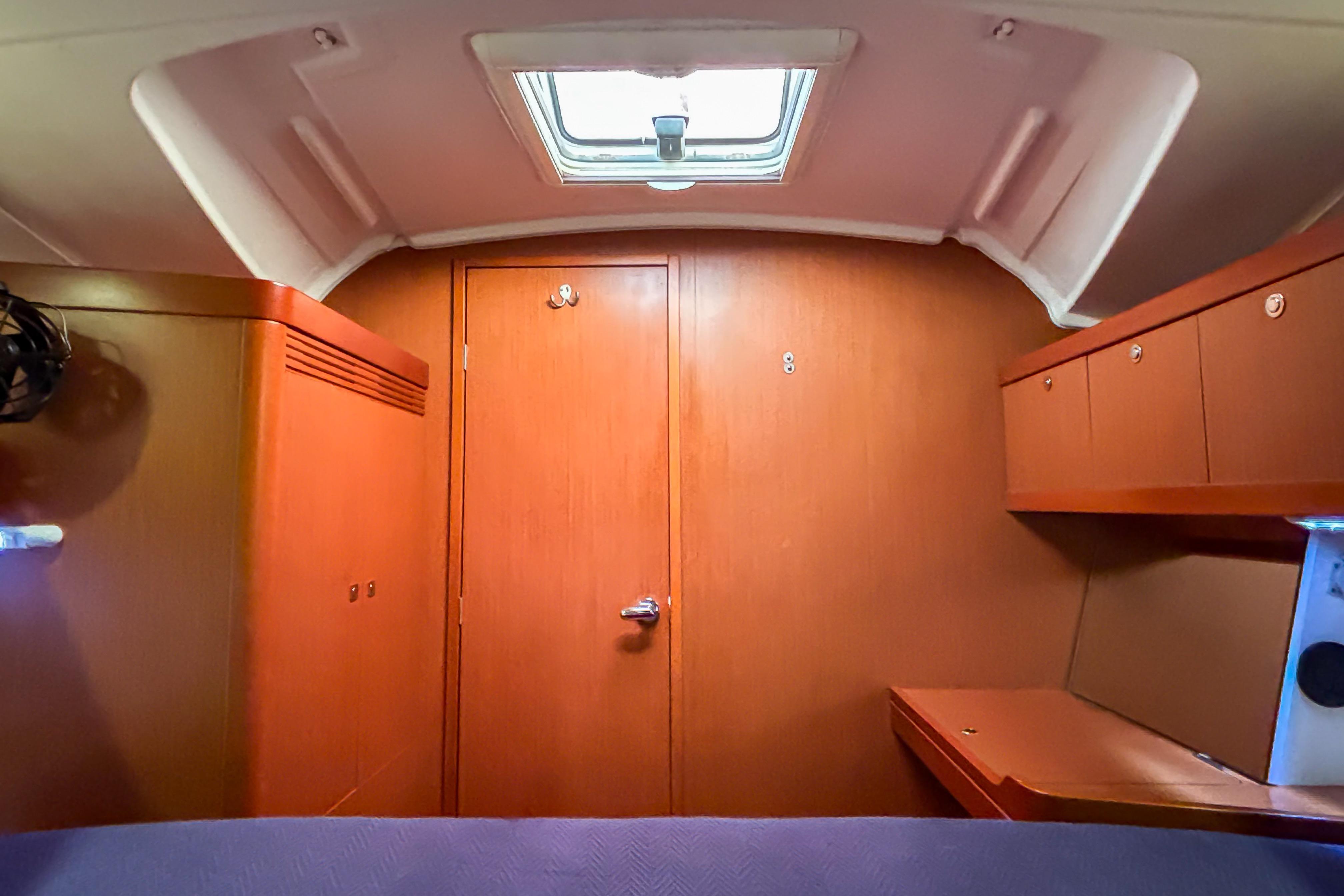 Interior cabin of 2015 Beneteau Oceanis 37 sailboat, featuring wood paneling and storage.