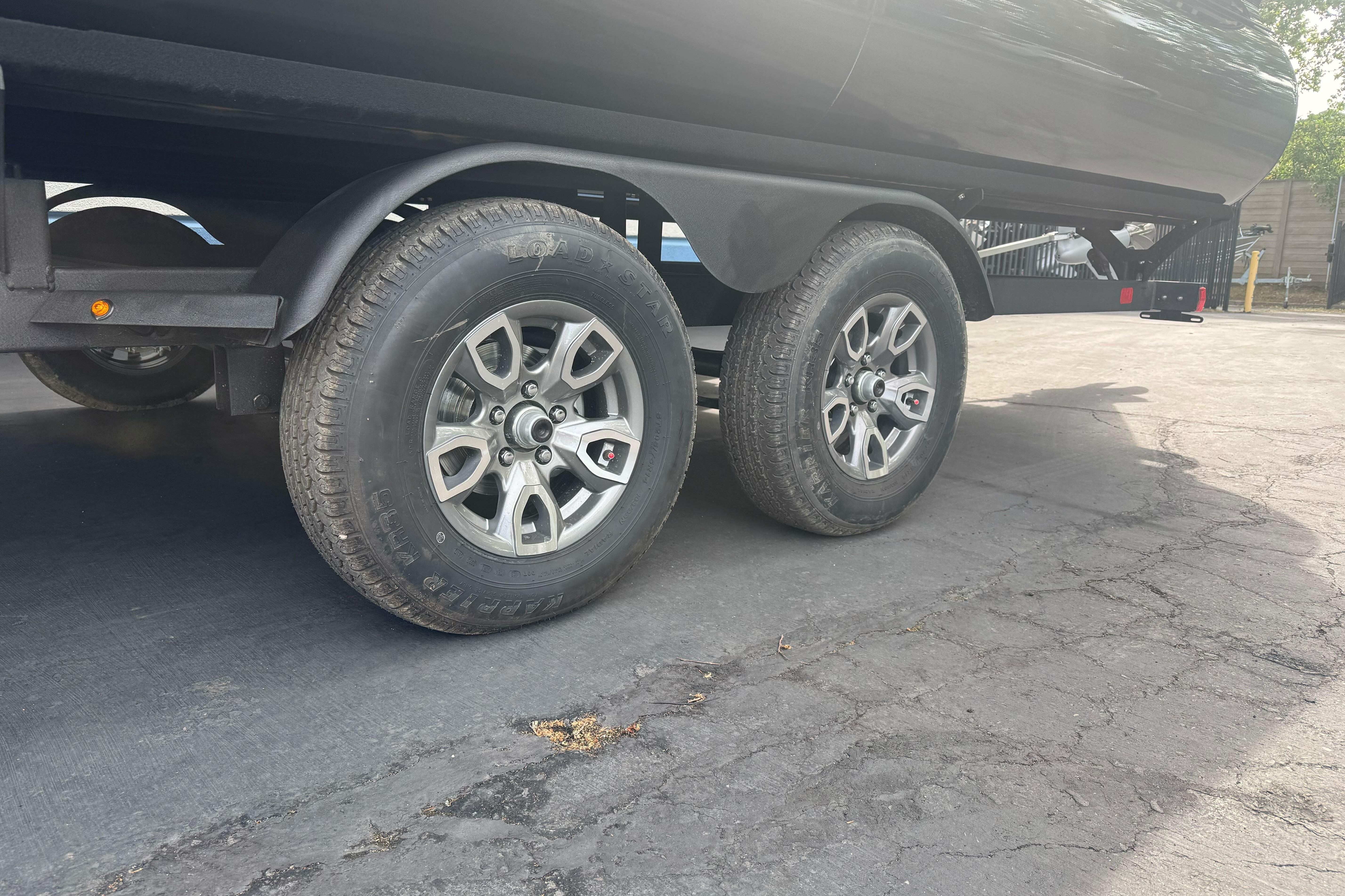 Trailer wheels of a 2026 Regency 250 DL on a paved surface.
