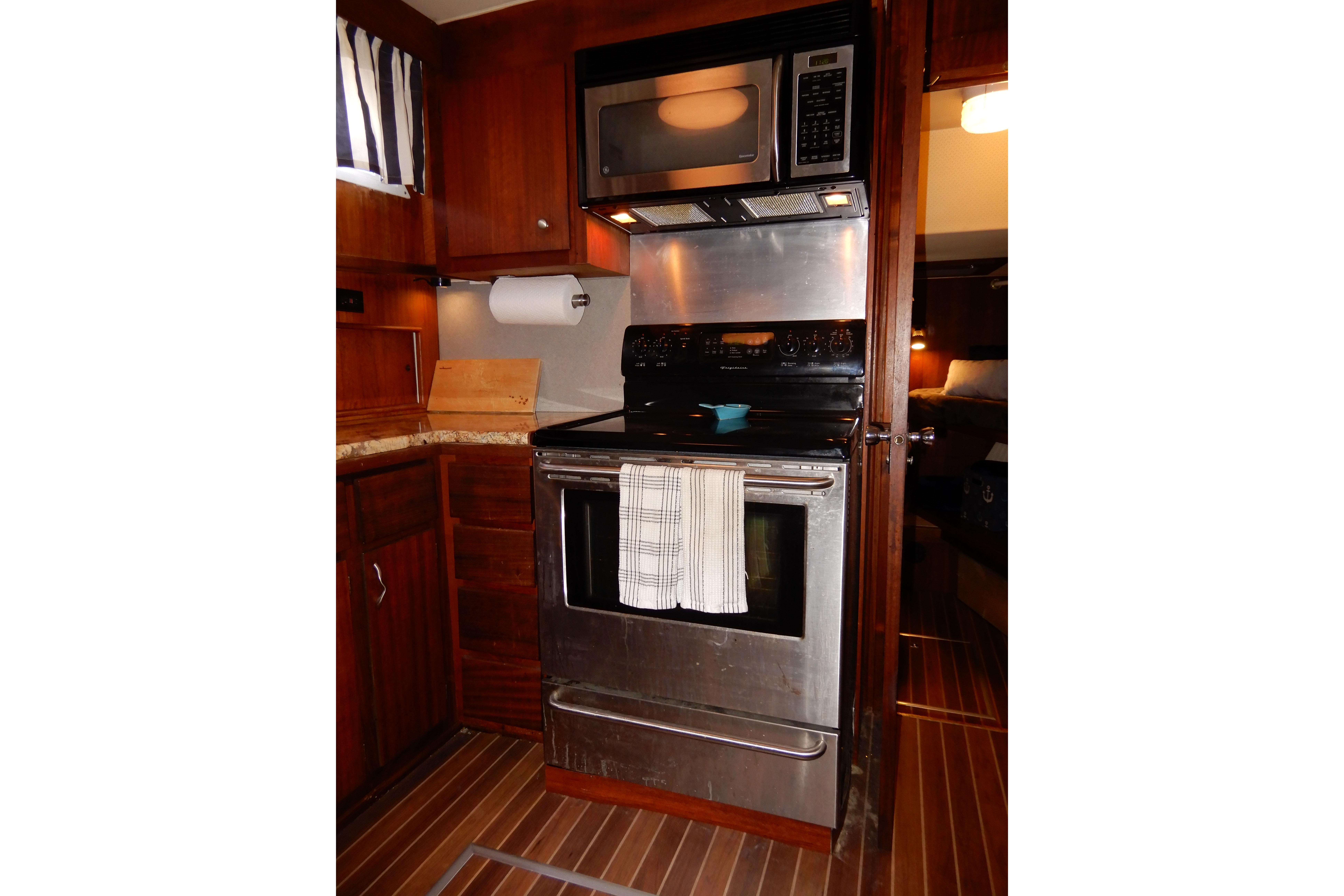 1974 Hatteras 53 Motor Yacht kitchen with stove, microwave, and wooden cabinetry.