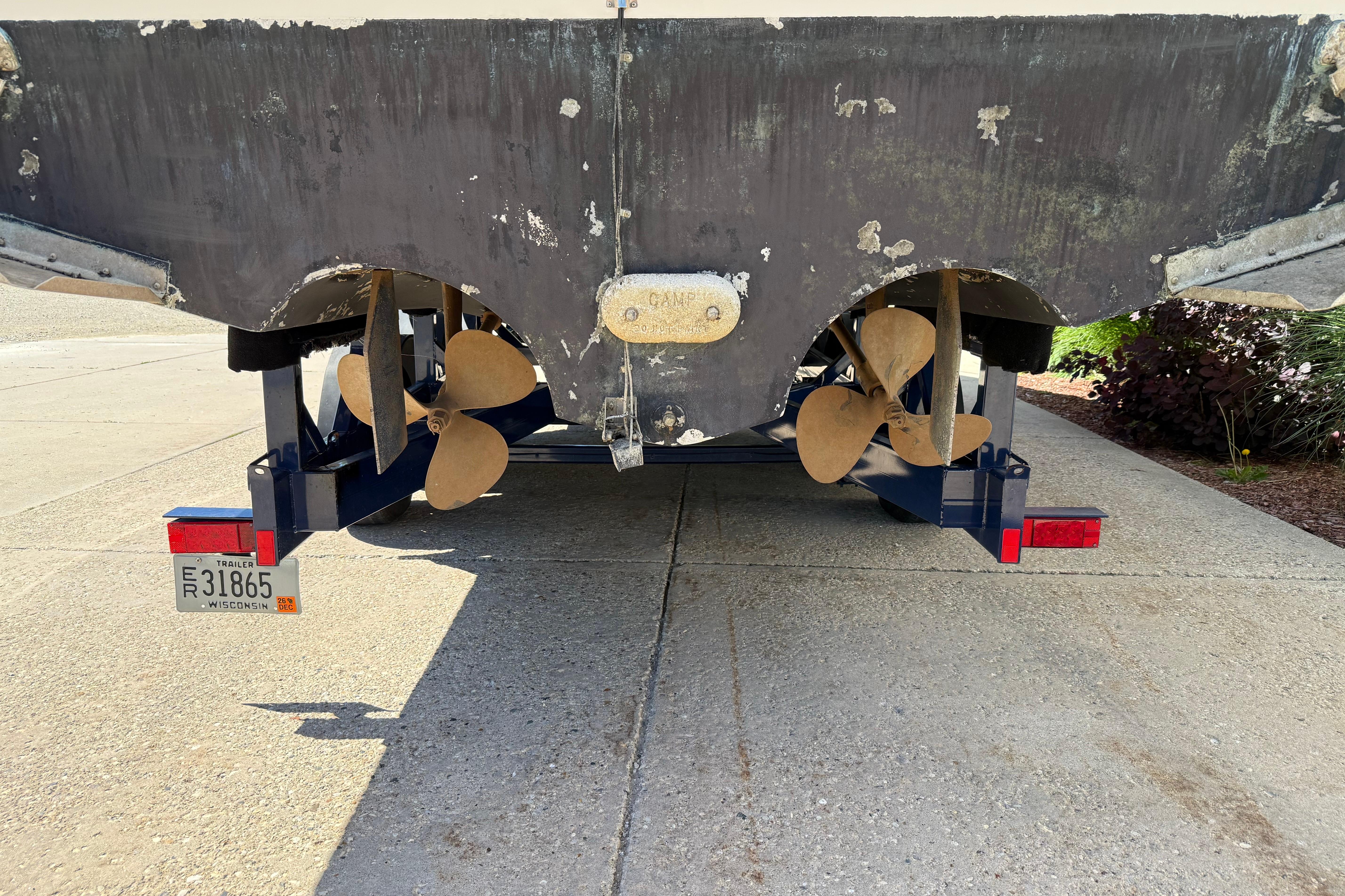 1990 Sea Ray 310 Express Cruiser on trailer, showing dual propellers and Wisconsin license plate.