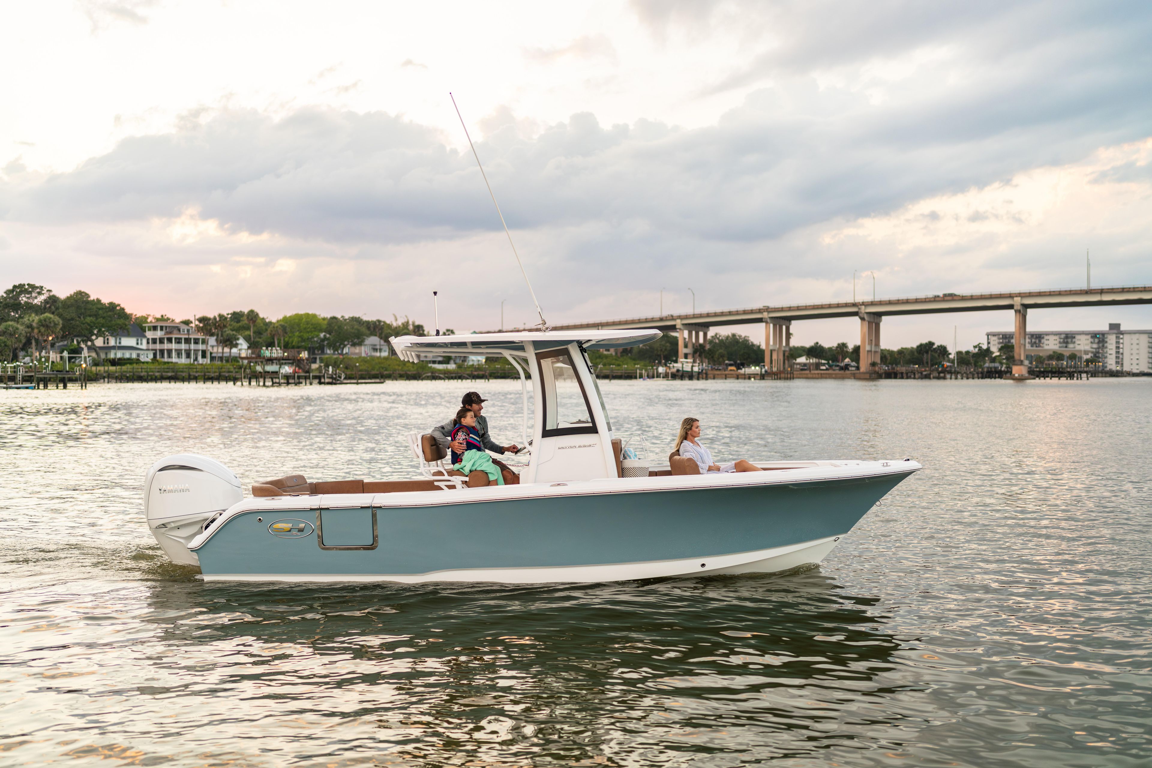 2026 Sea Hunt Ultra 235 SE boat cruising on a calm river near a bridge.