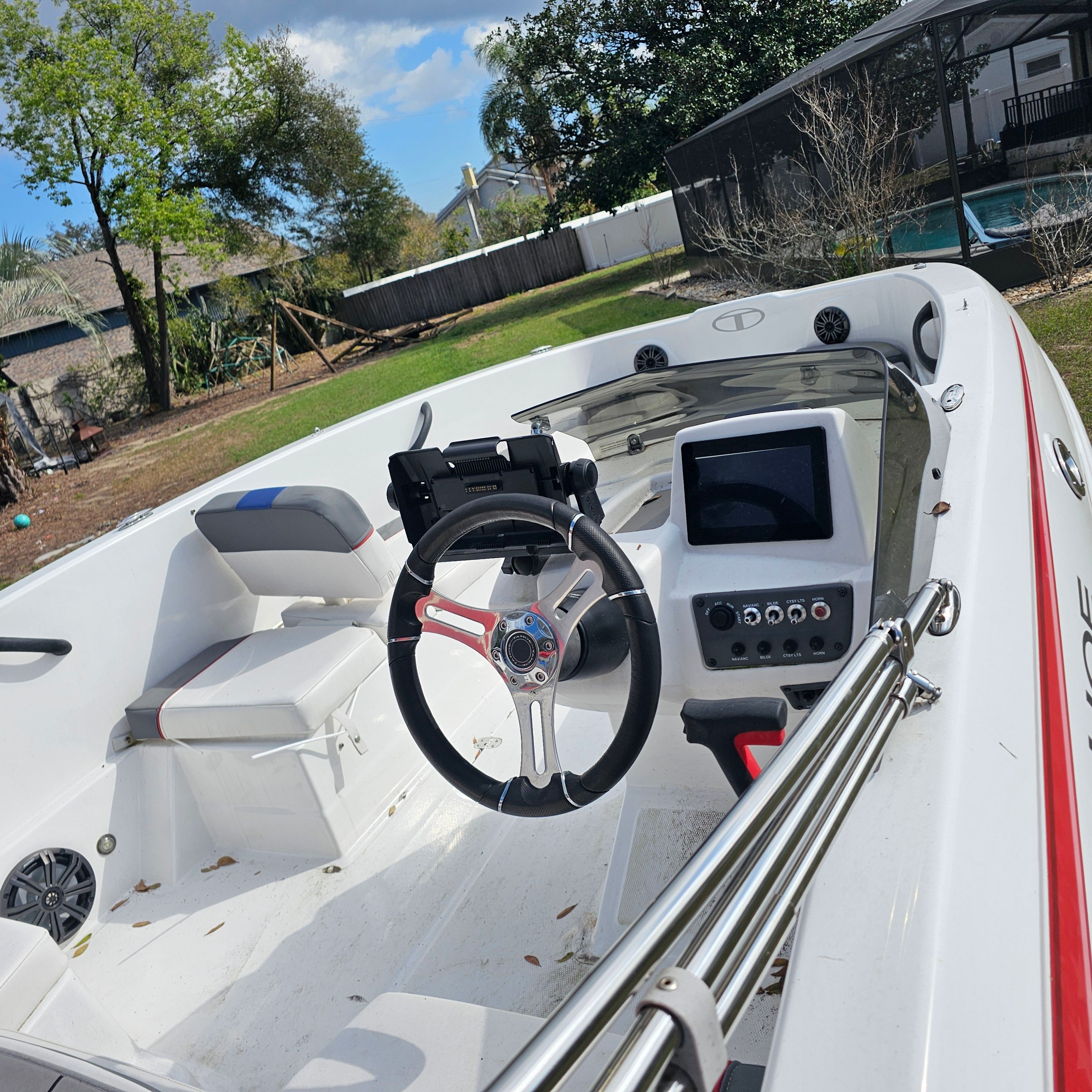 2024 Tahoe T18 boat interior with steering wheel and control panel, parked in a backyard.
